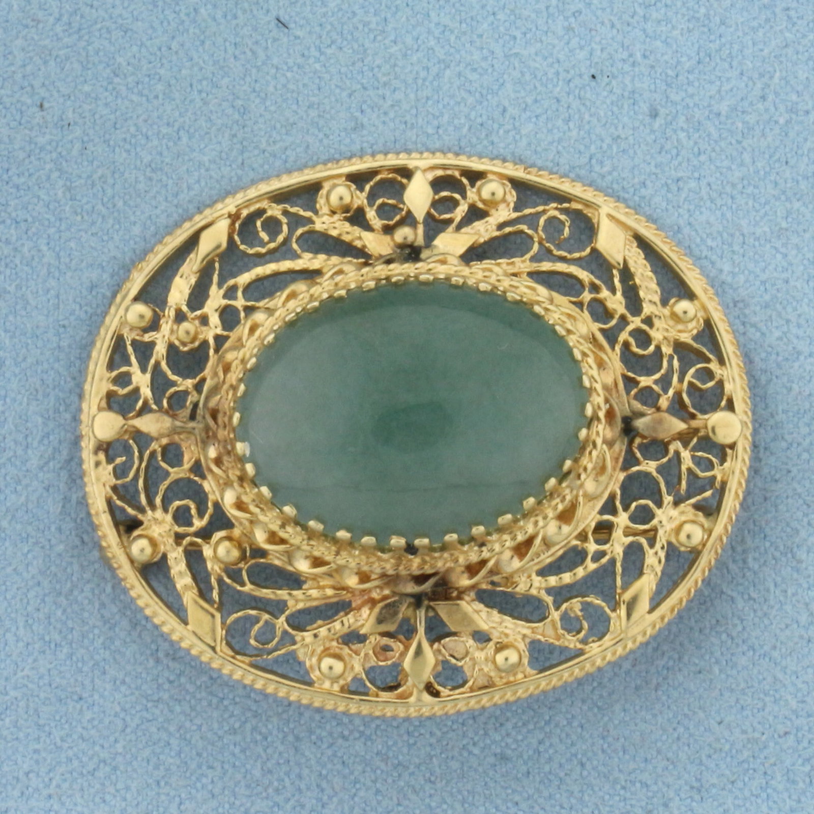 Vintage Designer Jade Filigree Pendant or Pin in 14K Yellow Gold: In 14K Yellow Gold. Contains a natural high quality 20x16mm Jade gemstone, approximately 15ct, with beautiful green color. 1 1/2" long, with bale for use as pendant. 12.7g