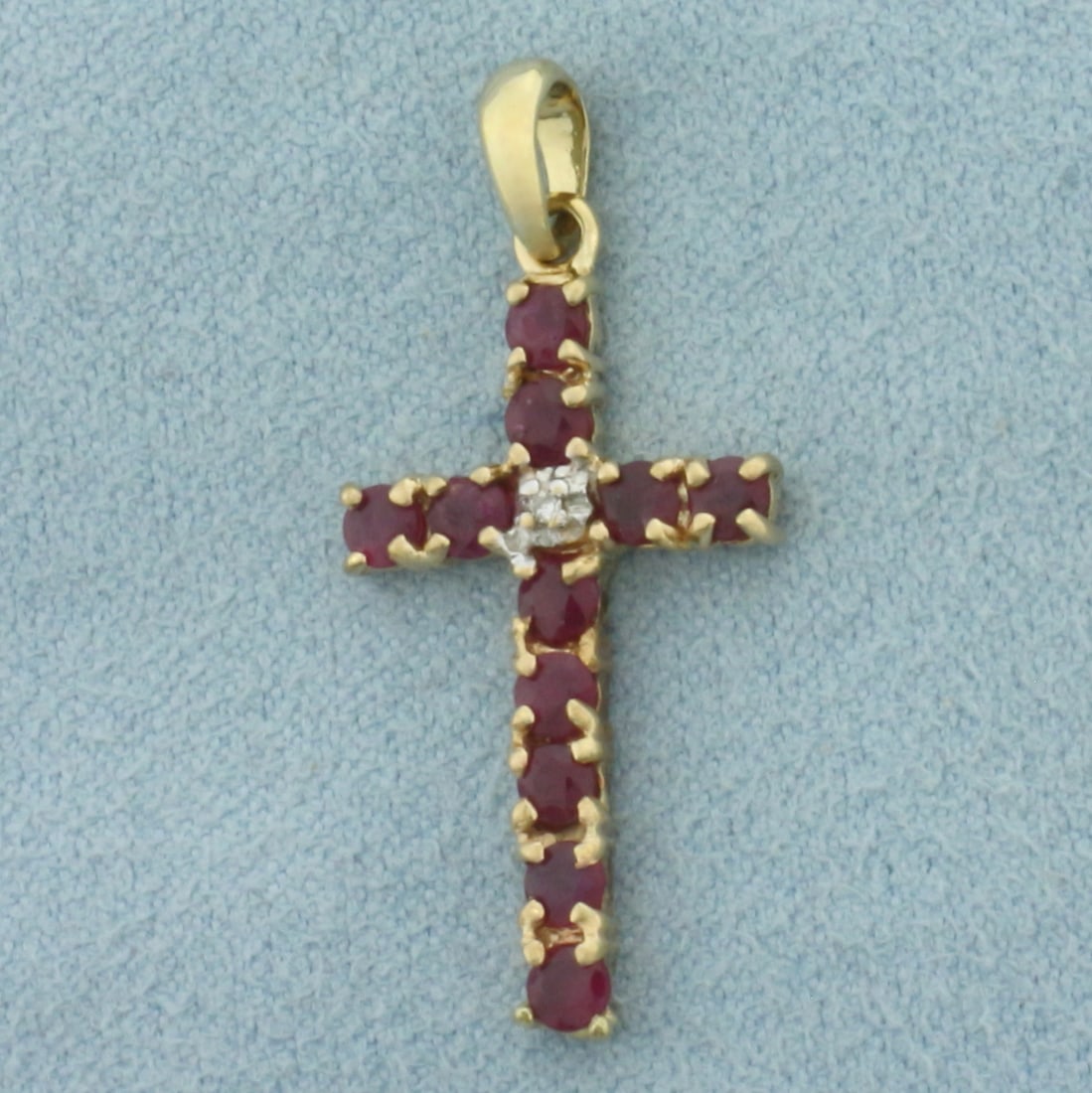 Ruby and Diamond Cross Pendant in 10k Yellow Gold: In 10k Yellow Gold. Contains eleven 2.6mm high quality natural Ruby gemstones with intense color. Also contains one .01ct high quality diamond. 1 1/8 inch long (including bale). 5/8 inch wide. 1.4g.