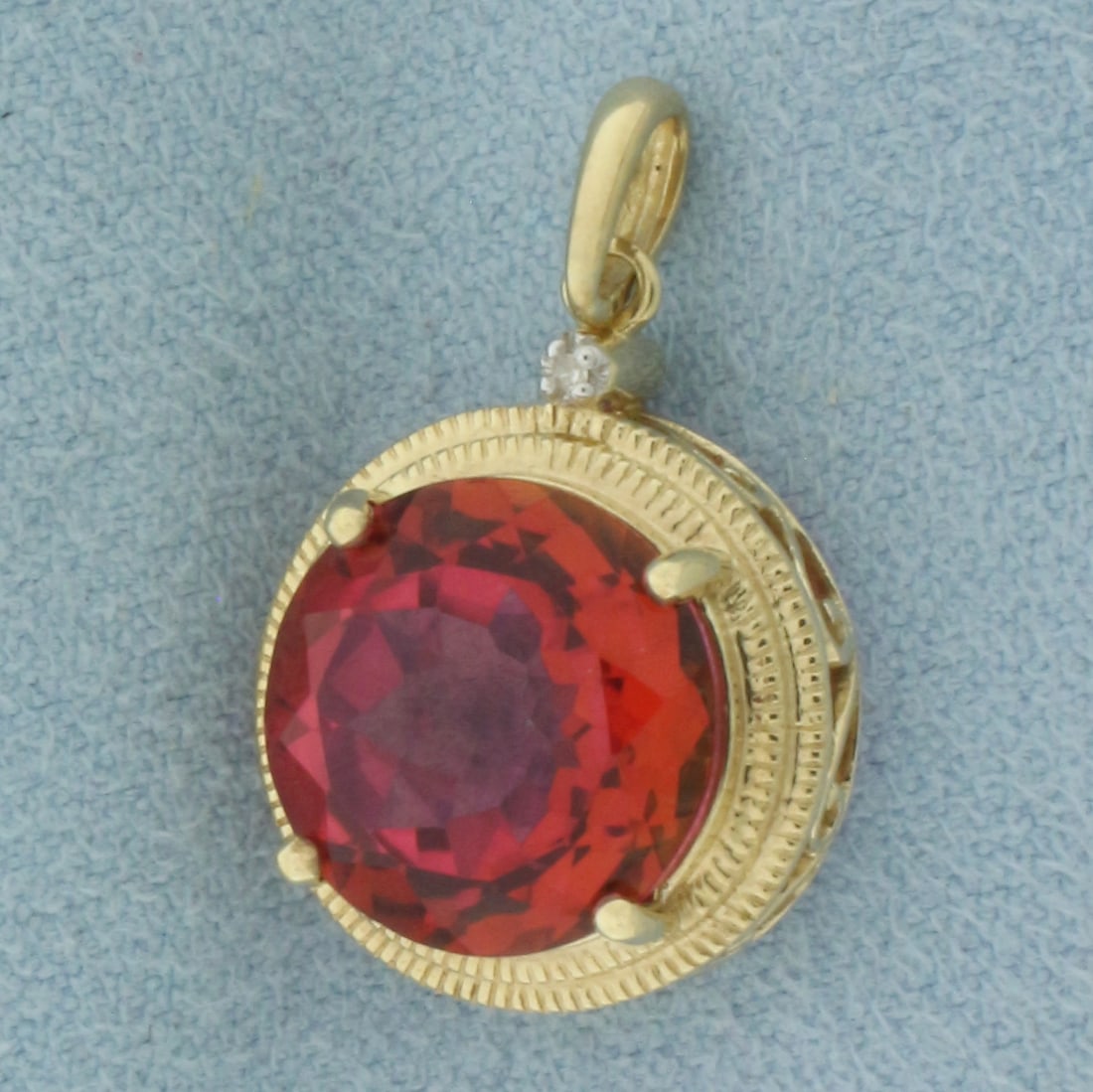 Red Topaz and Diamond Pendant in 10k Yellow Gold: In 10k Yellow Gold. Contains one 11.6mm high quality Topaz gemstone, approximately 5ct, intense color and excellent clarity. Also contains one high quality 1/2pt diamond. 1 inch long (including bale).