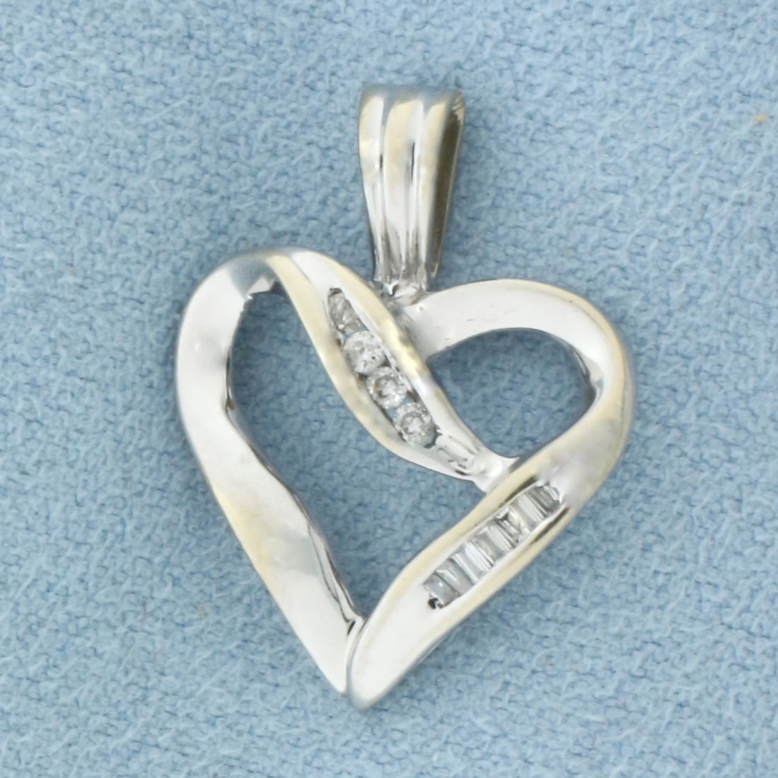 Diamond Heart Pendant in 10k White Gold: In 10k White Gold. Contains four round and six baguette high quality .01ct diamonds. 7/8 inch long. 5/8 inch wide. 1.6g.