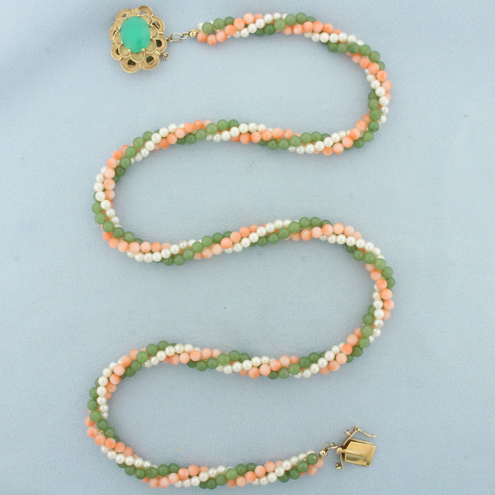 Jade, Pink Skin Coral, and Pearl Necklace in 14k Yellow Gold: In 14k yellow gold clasp. Contains three twisting strands of 4mm jade beads, pink skin coral beads, and cultured pearls with high luster. 22.5 inches long, 8mm wide (3 strands together). Decorative sl