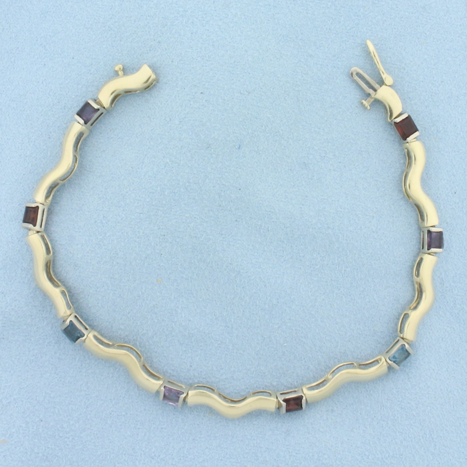 Rainbow Gemstone Wave Bracelet in 14K Yellow Gold: In 14k yellow gold. Measures7 5/8 inches long. Contains eight 4mm high quality natural gemstones - garnet, amethyst, and blue topaz, all with bright color and excellent clarity. Side clasp with safety