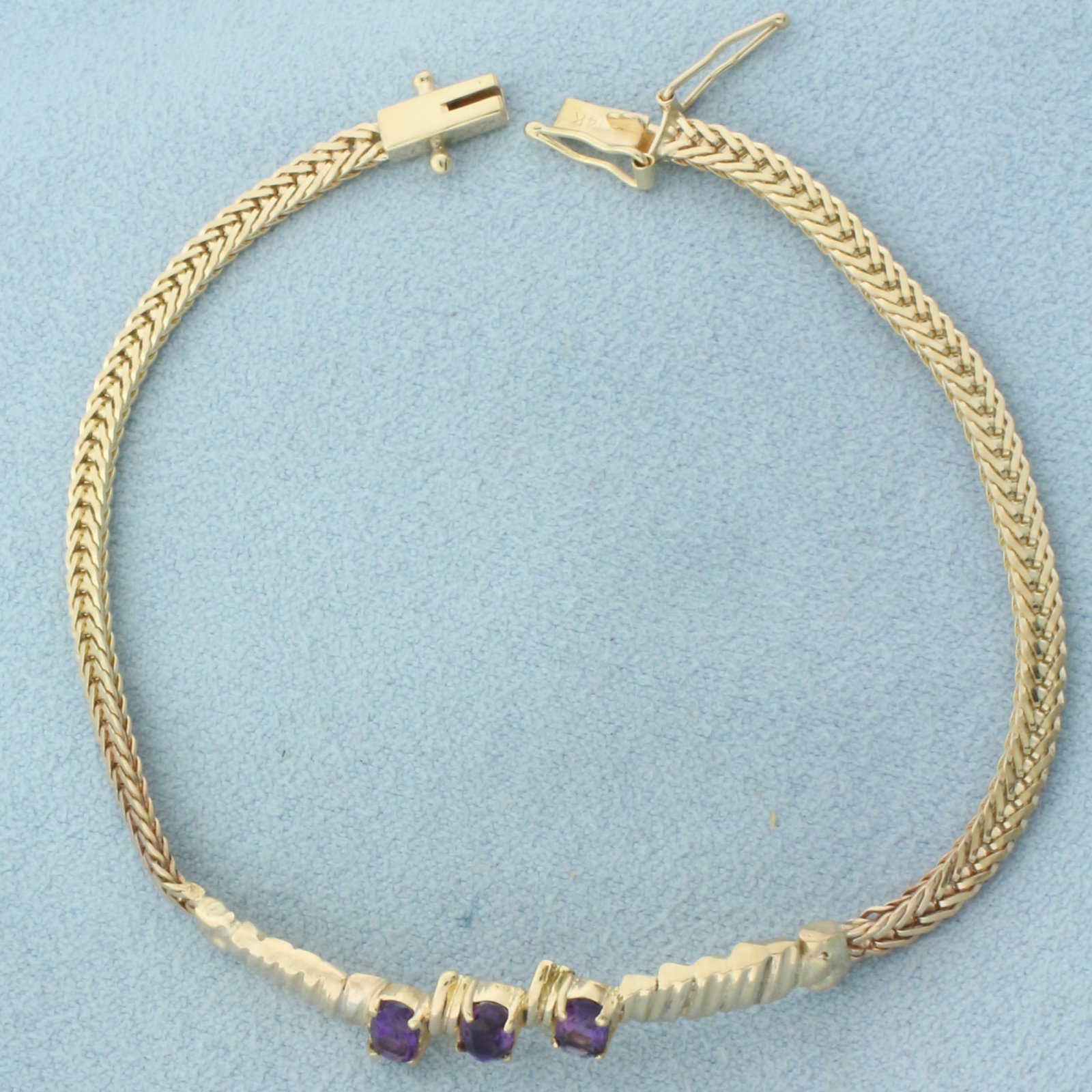 Amethyst Bracelet in 14k Yellow Gold: In 14k Yellow Gold. Contains three 5x3mm high quality natural Amethyst gemstones with intense color and excellent clarity. 6 3/4 inches long. 5.8mm wide in middle. Slide clasp with two safety latch. 5