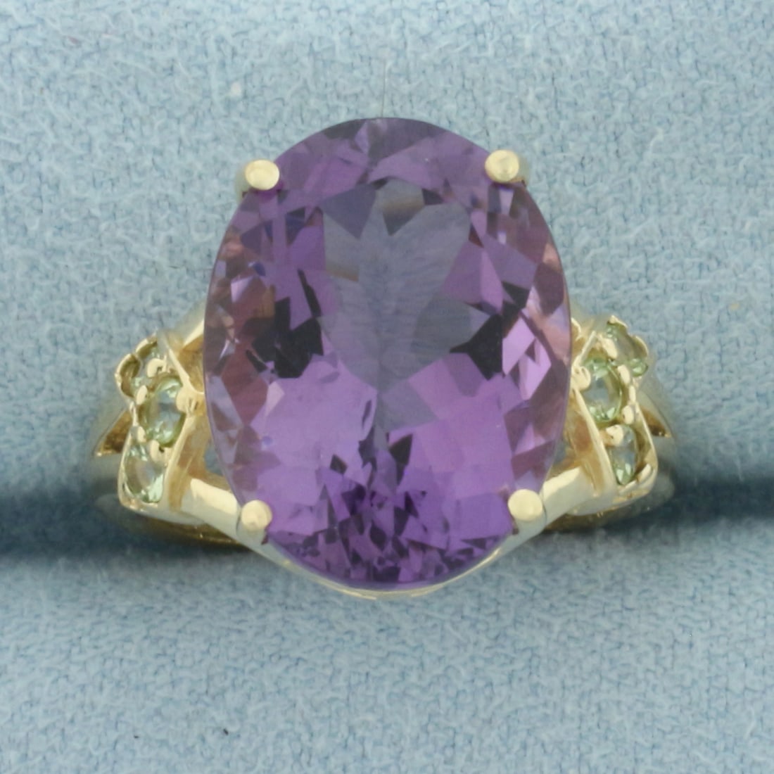 Amethyst Statement Ring in 10k Yellow Gold: In 10k Yellow Gold. Contains one 16x12mm high quality natural Amethyst gemstone, approximately 10cts, with intense color and excellent clarity. Also contains six 2mm high quality Green Amethyst gemsto