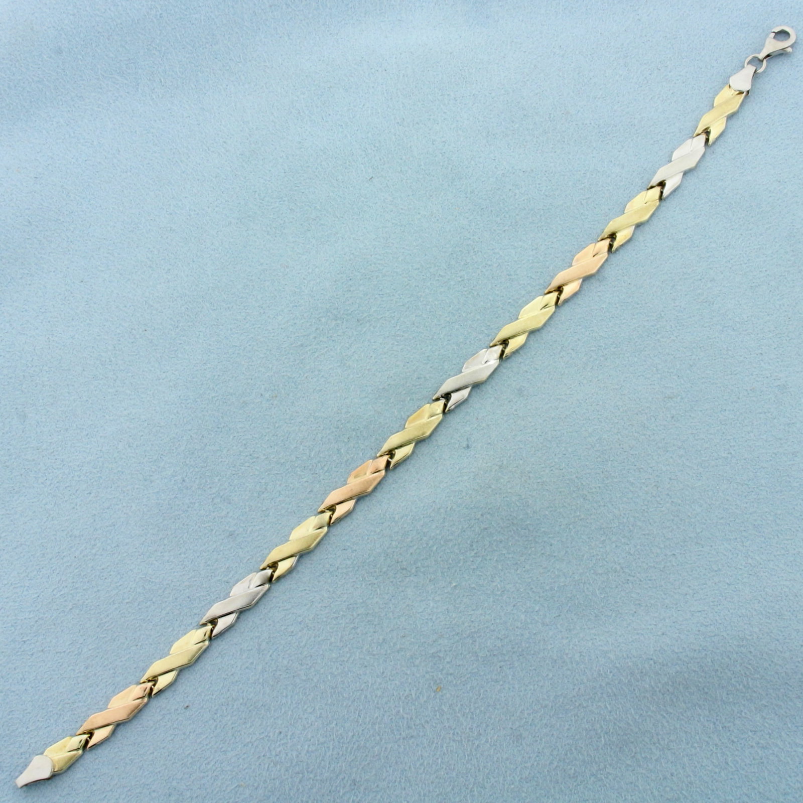 Tri-Color X Link Bracelet in 10k Gold and Sterling Silver: In 10k gold and sterling silver. 7 5/8 inches long. 4.7mm wide. Matte and high polish finish for unique look. Lobster clasp. 3.7g.