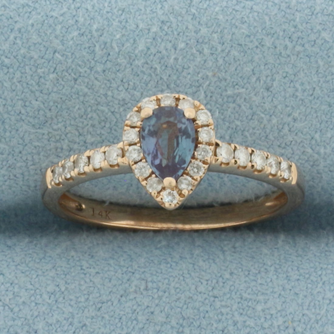 Alexandrite and Diamond Halo Ring in 14k Rose Gold: In 14k Rose Gold. Contains one 6x4mm high quality pear cut natural Alexandrite gemstone with dramatic color shift from aqua blue to purple. Also contains twenty-four .01ct high quality diamonds, VS cl