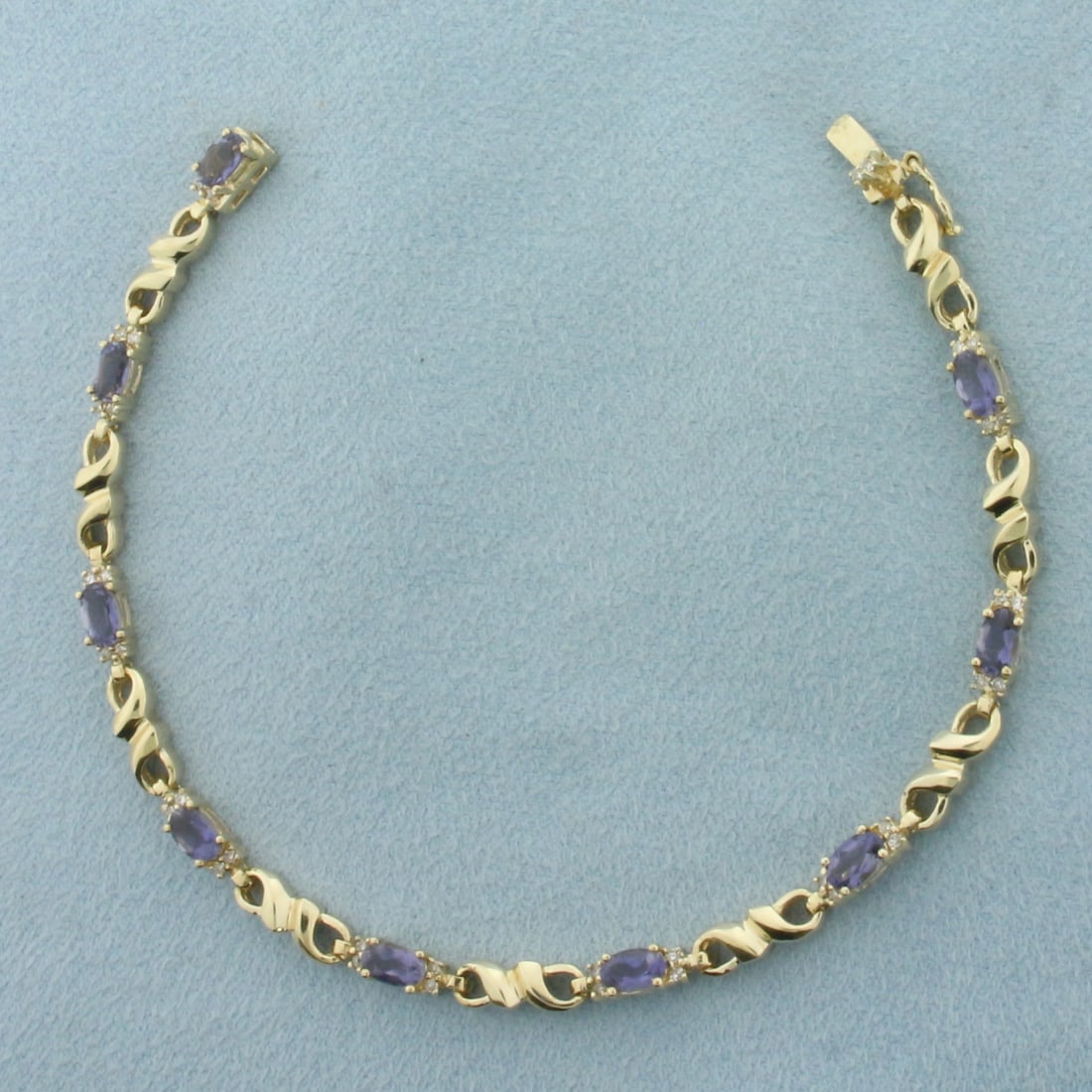Tanzanite And Diamond Infinity Link Bracelet in 10K Yellow Gold: In 10k yellow gold. 7 inches long. Contains 9 oval cut high quality Tanzanite Gemstones, 3x5mm each, 2.5ct TW, with excellent color and clarity. Accented with 34 high quality 1/2pt diamonds. Concealed