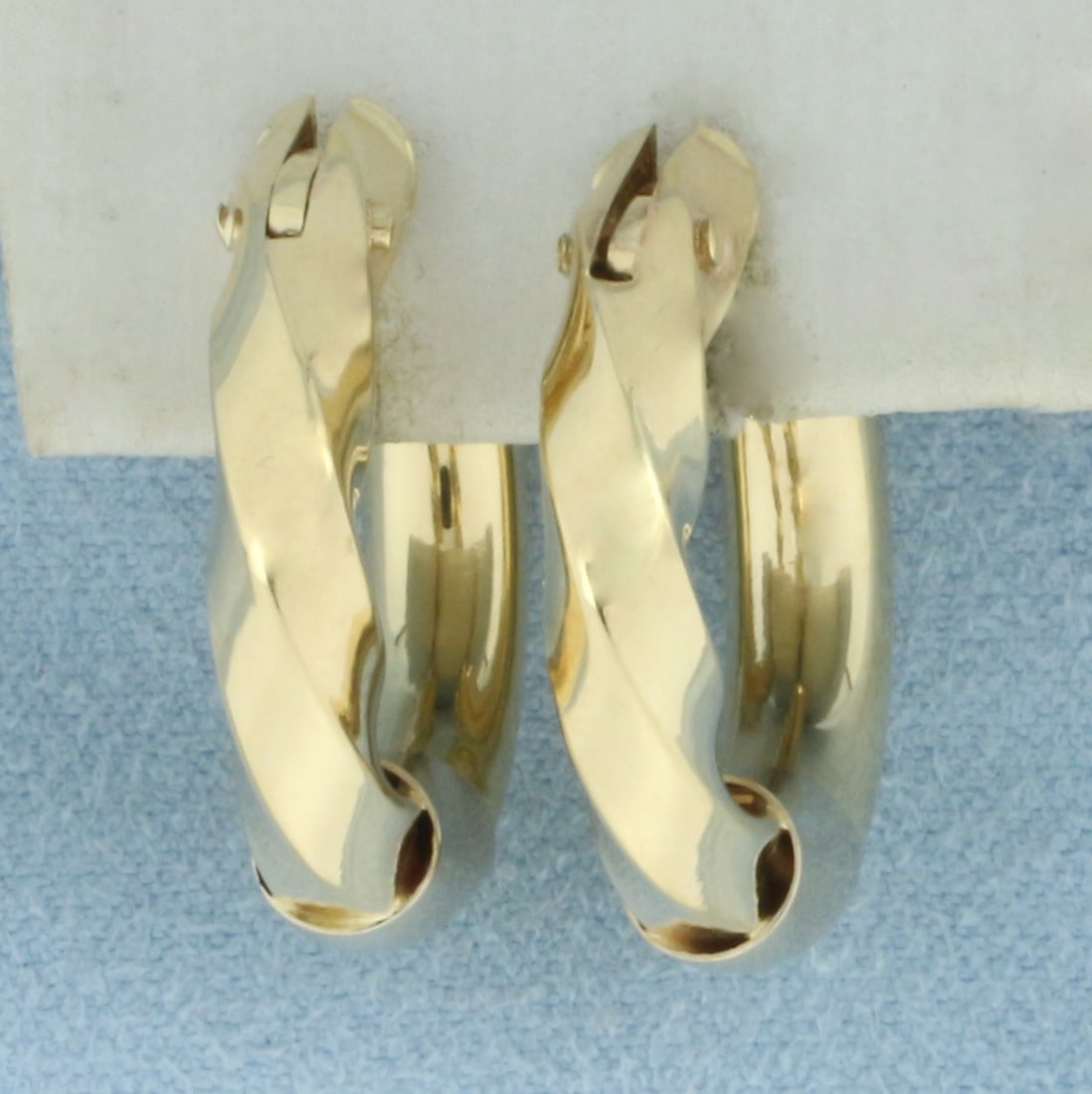 Twisting Design Hoop Earrings in 14k Yellow Gold: In 14k Yellow Gold. 7/8 inch long. 7/8 inch wide. 4.8mm wide tubes. Leverbacks. 4.9g.