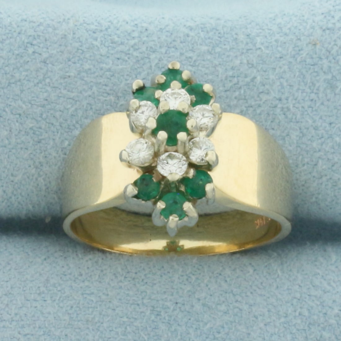 Emerald And Diamond Ring in 14K Yellow Gold: In 14k yellow gold. 15mm wide at top of ring. Contains one 3.4mm and six 2.7mm high quality natural Emerald Gemstones with vibrant color. Accented by six .07ct high quality diamonds, VS clarity/F colo
