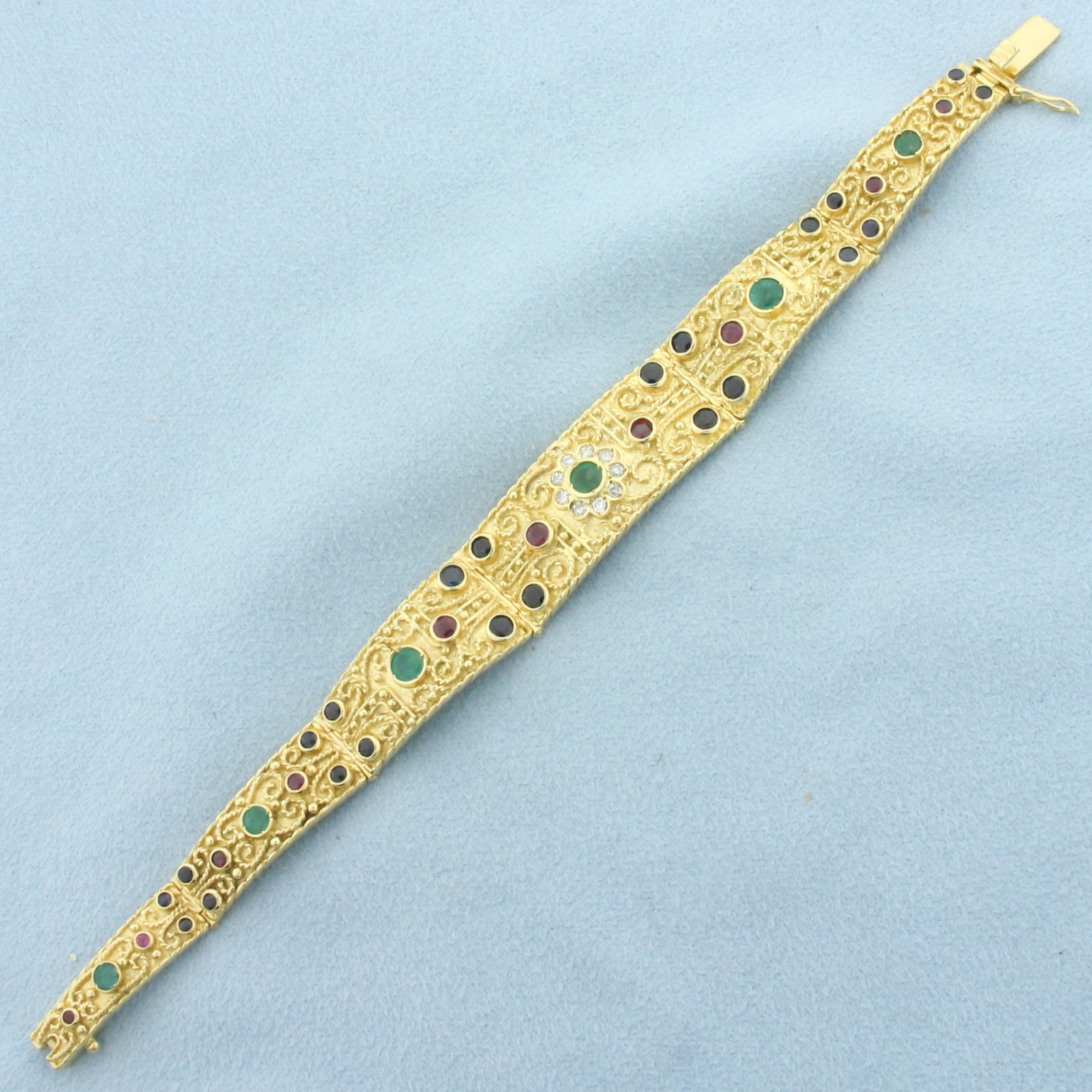 Greek Designer Kouzoupis Emerald, Sapphire, Ruby, and Diamond Bracelet in 18k Yellow Gold: In 18k Yellow Gold. Contains six Emerald, ten Ruby, and twenty two Sapphire high quality natural gemstones ranging from 1.75 to 4mm each, intense color and excellent clarity. Also contains nine .03ct