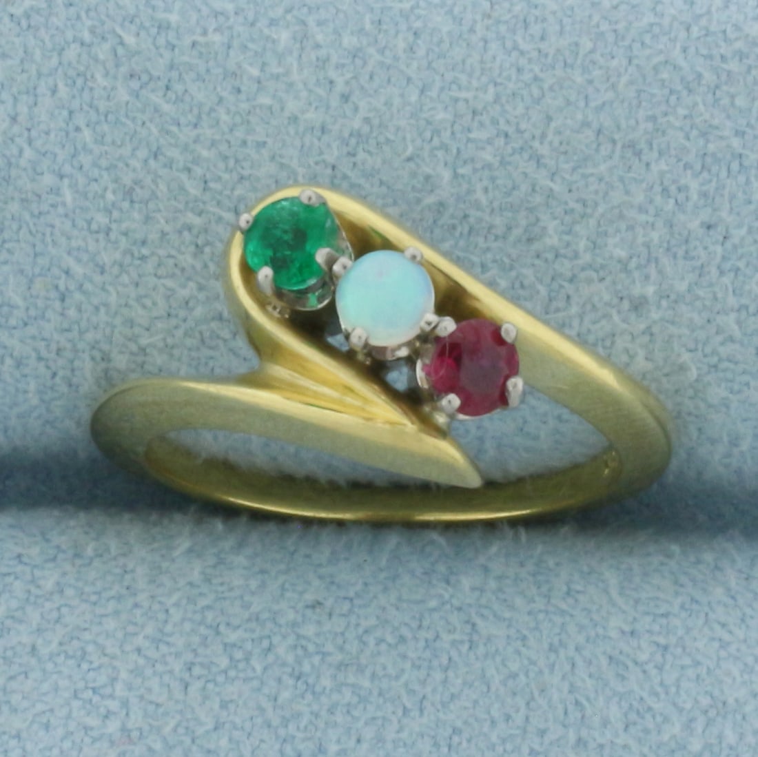 Emerald, Opal, and Ruby Ring in 18k Yellow Gold: In 18k Yellow Gold. Contains high quality natural 3.1mm gemstones: Emerald, Opal, and Ruby, all with intense color. 12mm wide at widest point. Size 5.5. 4.4g.