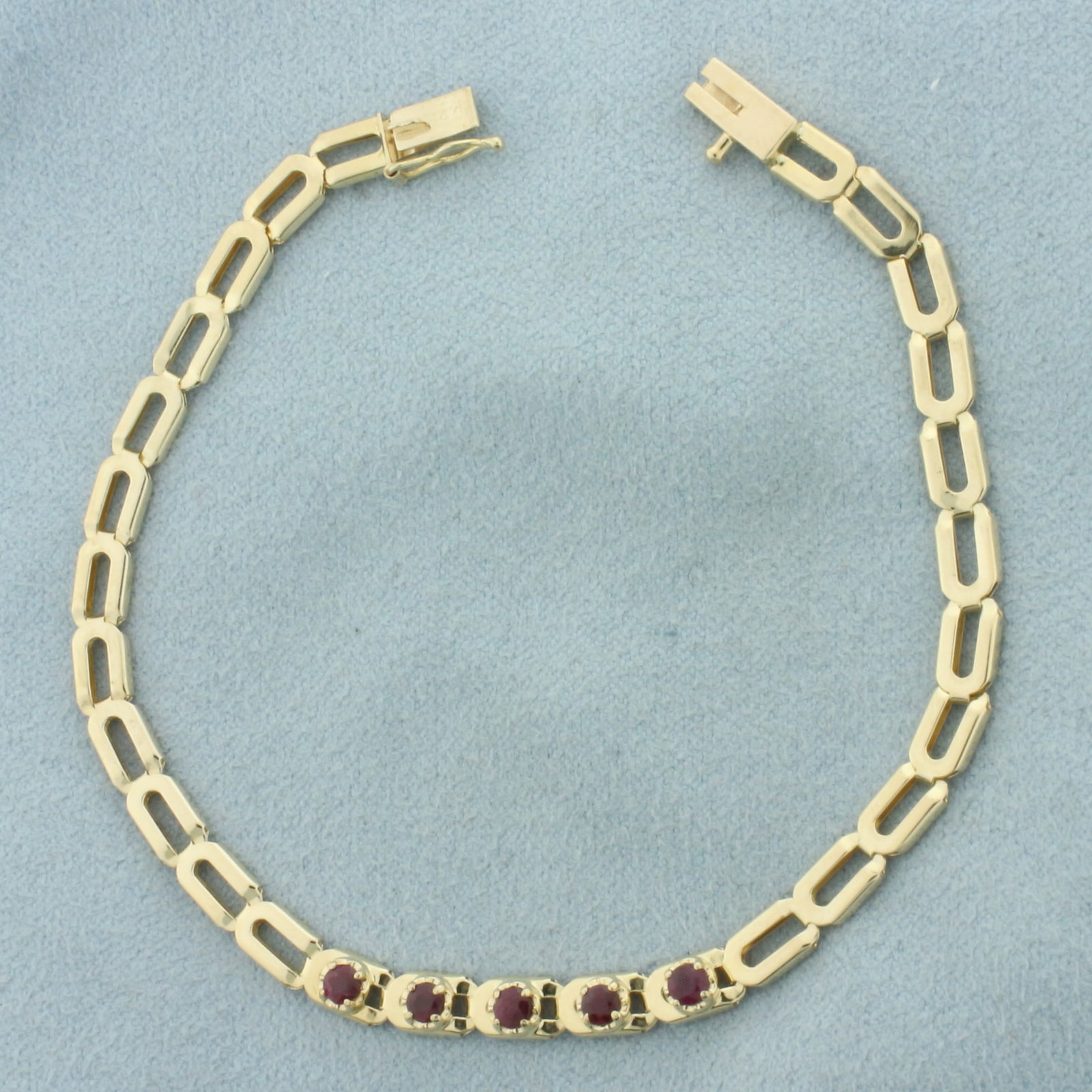 Ruby Bracelet in 14k Yellow Gold: In 14k Yellow Gold. Contains five 2.5mm high quality natural Ruby gemstones with intense color. 7 inches long. 1/8 inch wide. Slide clasp with safety latch. 3.9g.