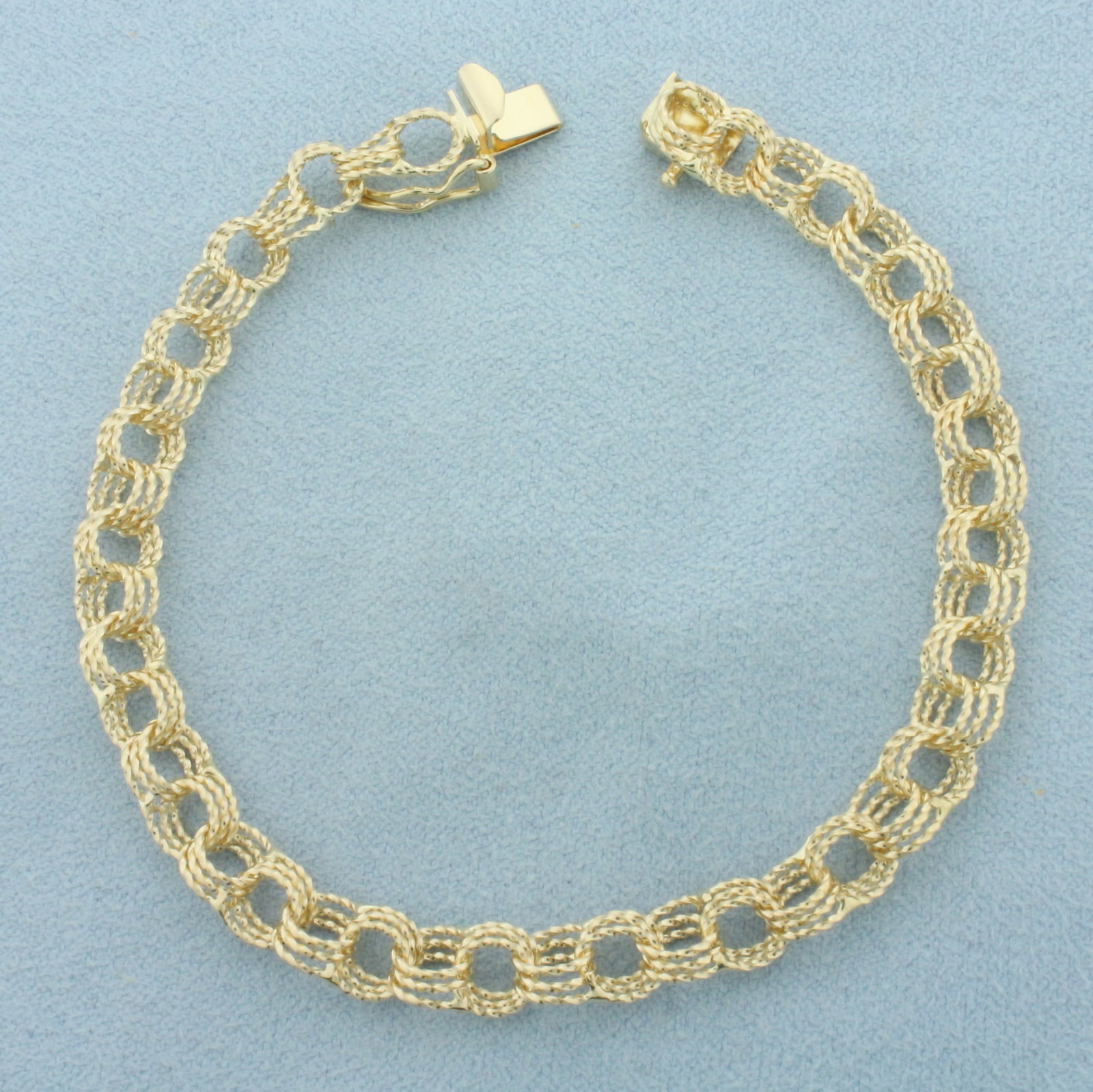 Triple Loop Charm Bracelet in 14k Yellow Gold: In 14k Yellow Gold. 7 1/8 inches long. 6.4mm wide. Concealed slide clasp with safety latch. 7.5g.