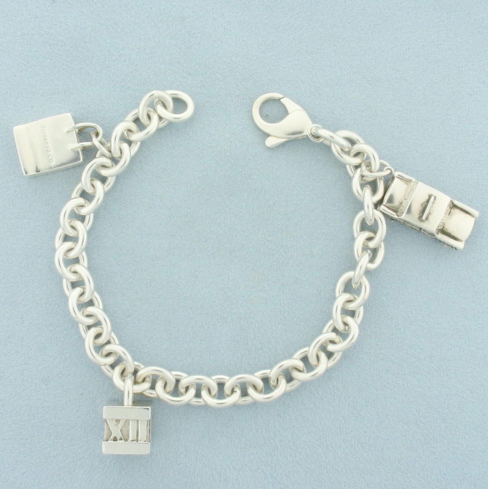 Tiffany and Co. Vintage Charm Bracelet with Taxi, Shopping Bag, Atlas Cube Charms: .925 Sterling silver, Guaranteed Authentic. 8 inches long. Contains, 3 rare charms (all authentic Tiffany and Co. sterling silver charms): taxi cab, shopping bag, Atlas cube. 48.8g.