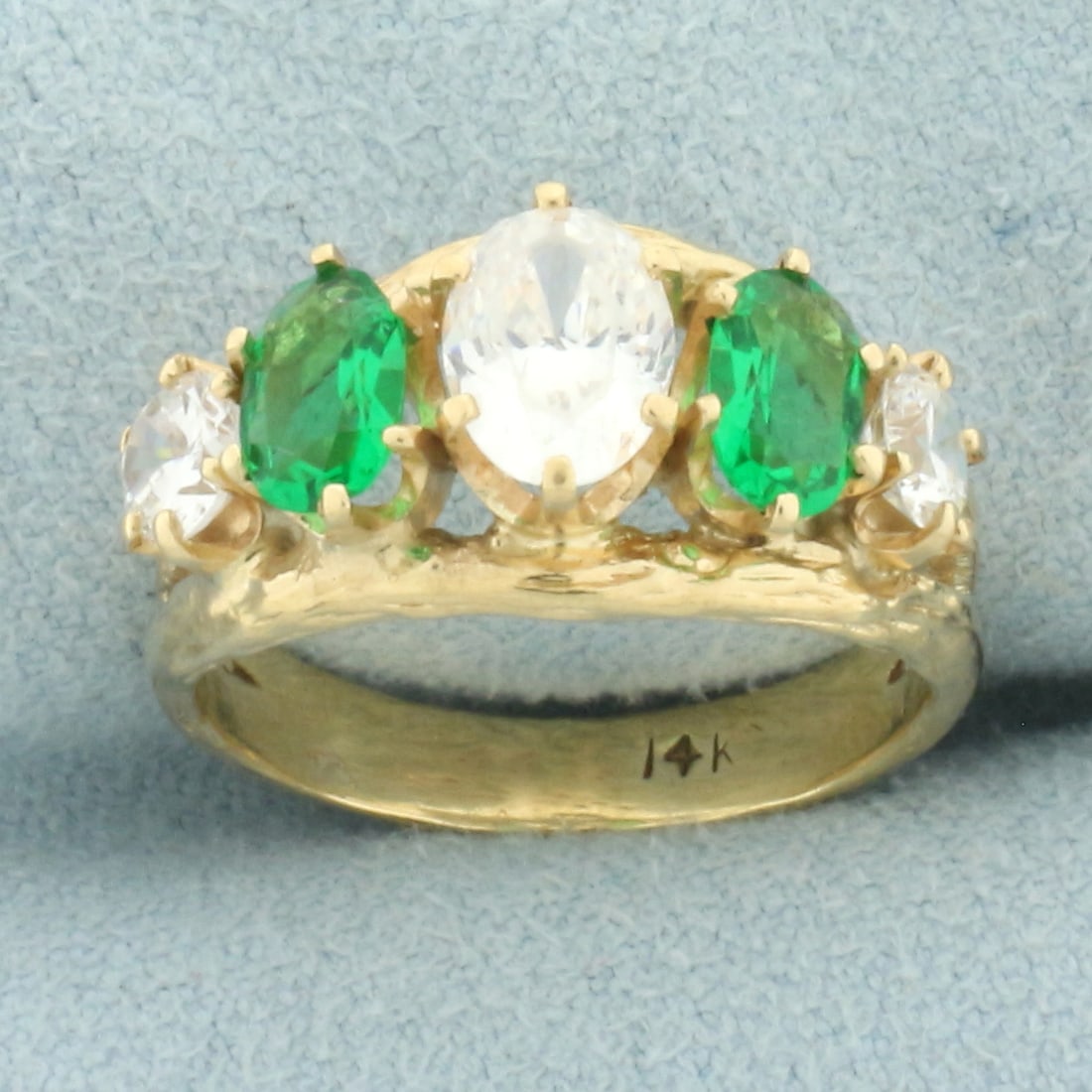 Synthetic Diamond and Emerald 5-Stone Ring in 14k Yellow Gold: In 14k yellow gold. Contains 1 high quality 7mm by 5mm oval and two 4mm round synthetic diamonds with excellent cut and clarity for extra brilliance. Also contains 2 oval 6mm by 4mm synthetic emerald 