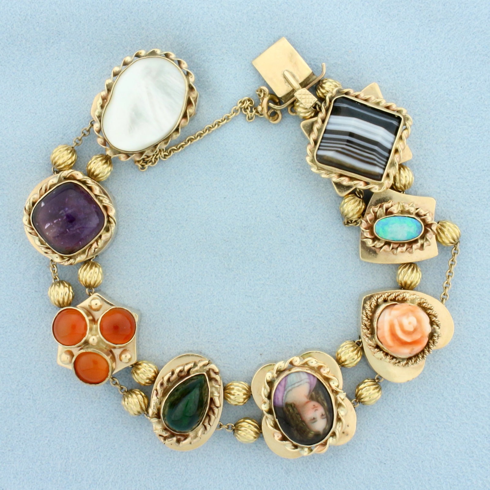Vintage Gemstone Large Slide Charm Bracelet in 14k Yellow Gold: In 14k Yellow Gold. Contains: 14mm Agate gemstone, 9.5x5mm Opal gemstone with intense play of color, 10mm Rose shaped Coral gemstone, 15mm hand painted left gaze female cameo, 12.5mm Jade gemstone, 12