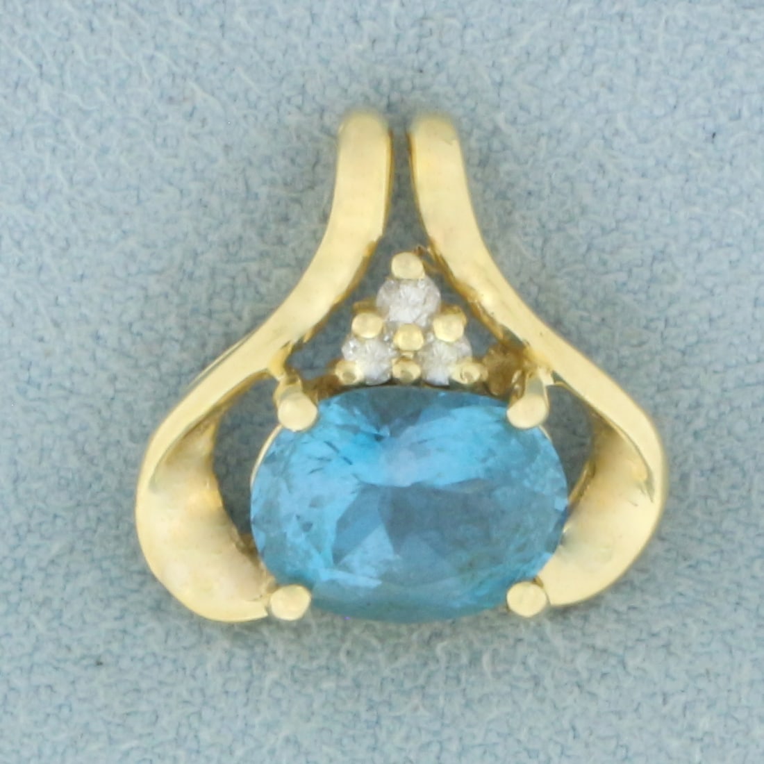 Swiss Blue Topaz and Diamond Pendant in 14k Yellow Gold: In 14k Yellow Gold. Contains one 9x7mm high quality natural Swiss Blue Topaz gemstone, approximately 2.5cts, with electric blue color and excellent clarity. Also contains three .02high quality diamond