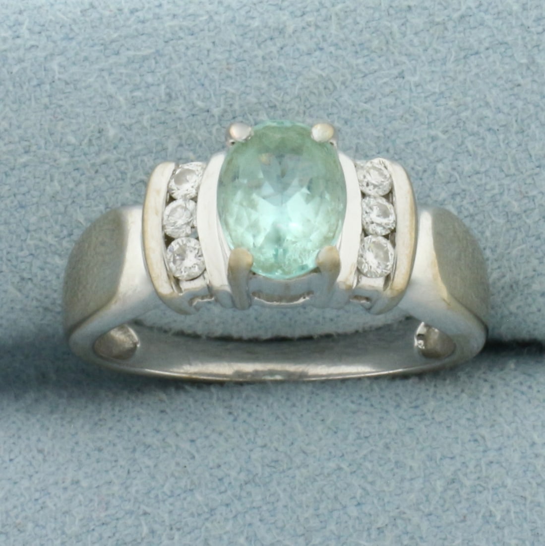 Paraiba Tourmaline and Diamond Ring in 18k White Gold: In 18k White Gold. Contains one 8x6mm high quality oval cut natural Paraiba Tourmaline gemstone, approximately 1ct, with vibrant color and excellent clarity. Also contains six .03ct high quality