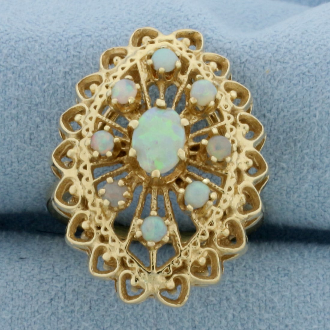 Vintage Opal Statement Ring in 14k Yellow Gold: In 14k Yellow Gold. Contains one 7mm and eight 2.4mm high quality natural Opal gemstones with excellent play of pink, blue, purple, and green. 1 inch long. 3/4 inch wide. Size 8. 7.0g.