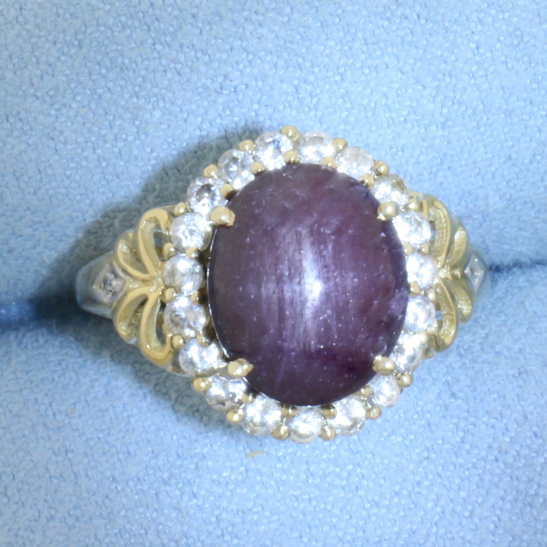 Natural Star Ruby and Diamond Halo Ring in 10k Yellow Gold: In 10k Yellow Gold. Contains one 12x10x8mm high quality natural Star Ruby gemstone with distinct "star" under light. Also contains twenty-one high quality .03ct diamonds, SI clarity/H color. 16mm wide