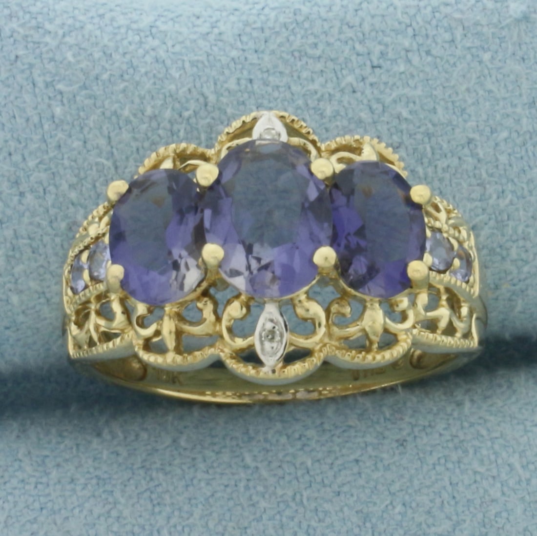 Tanzanite and Diamond Filigree Ring in 10k Yellow Gold: In 10k Yellow Gold. Contains one 8x6mm, two 7x5mm, and four 2mm high quality natural Tanzanite gemstones with vibrant color and excellent clarity. Also contains two high quality 1/2pt diamonds. 14mm