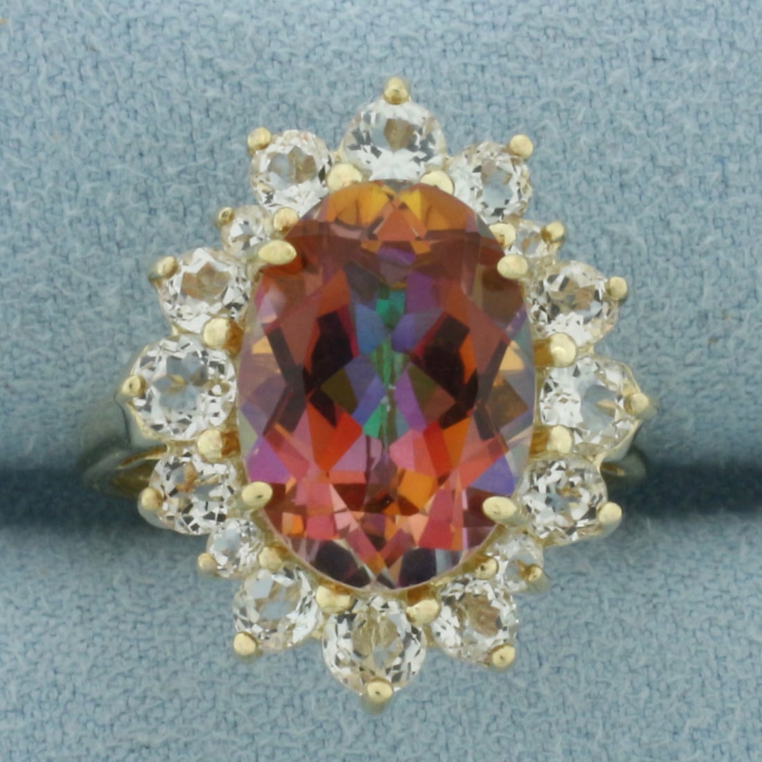 Sunrise Mystic Topaz and White Sapphire Halo Ring in 10k Yellow Gold: In 10k Yellow Gold. Contains one 14x10mm high quality oval Sunrise Mystic Topaz gemstone, approximately 6cts, with vibrant color and excellent clarity. Also contains four 3.5mm, eight 3mm, and four
