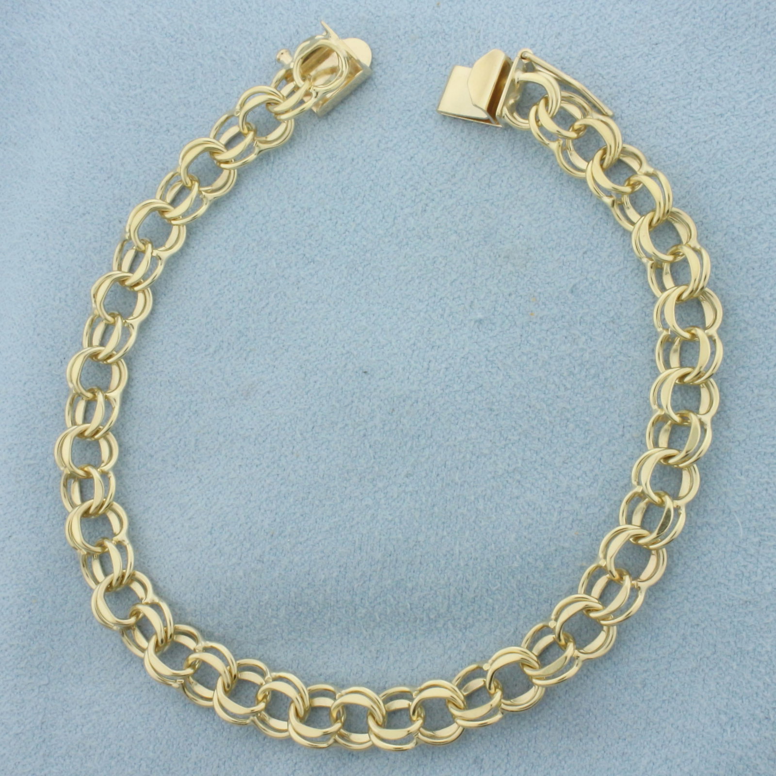 Double Loop Charm Bracelet in 14k Yellow Gold: In 14k Yellow Gold. 7 1/2 inches long. 6.5mm wide. Concealed slide clasp with safety latch. 10.8g.