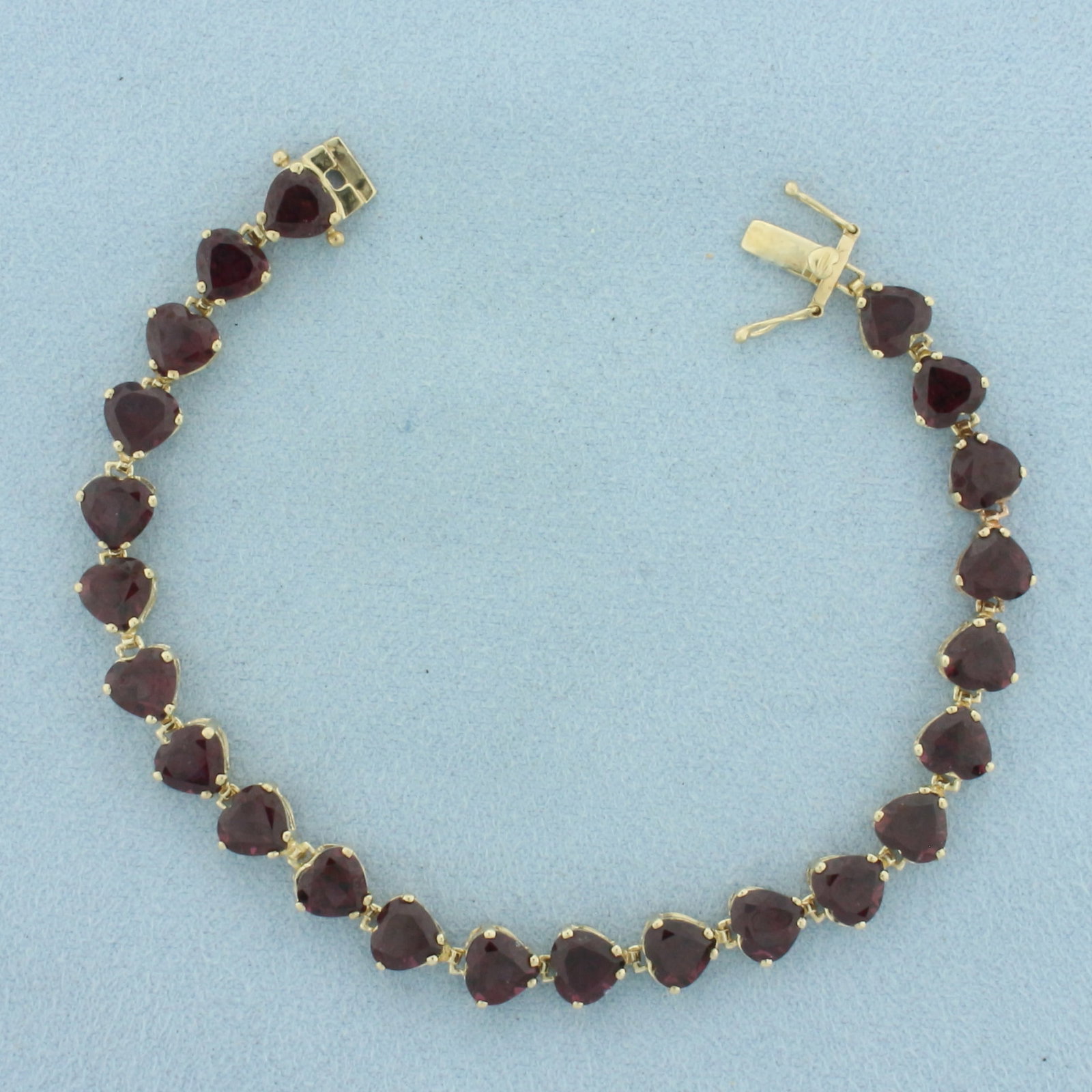 Heart Cut Garnet Tennis Bracelet in 10K Yellow Gold: In 10k yellow gold. 7 inches long. Contains 23 high quality 6mm natural Garnet heart shaped gemstones with deep color and excellent clarity. Slide clasp with double safety latches. 9.4g.