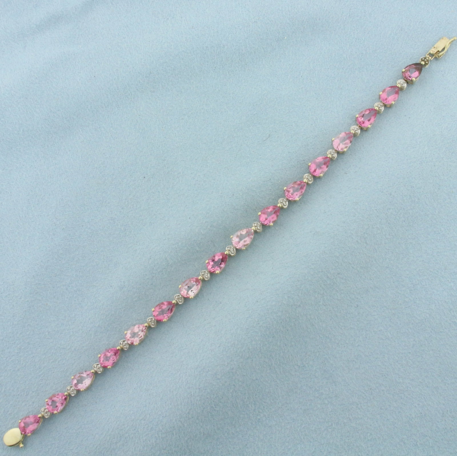 Pink Topaz And Diamond Bracelet in 10K Yellow Gold: In 10k yellow gold. 6 37/8 inches long. Contains 16 pear cut Pink Topaz gemstones, 5x7mm each, vibrant range of light to intense pink colors, and excellent clarity. Accented with 7 high quality 1/2pt 
