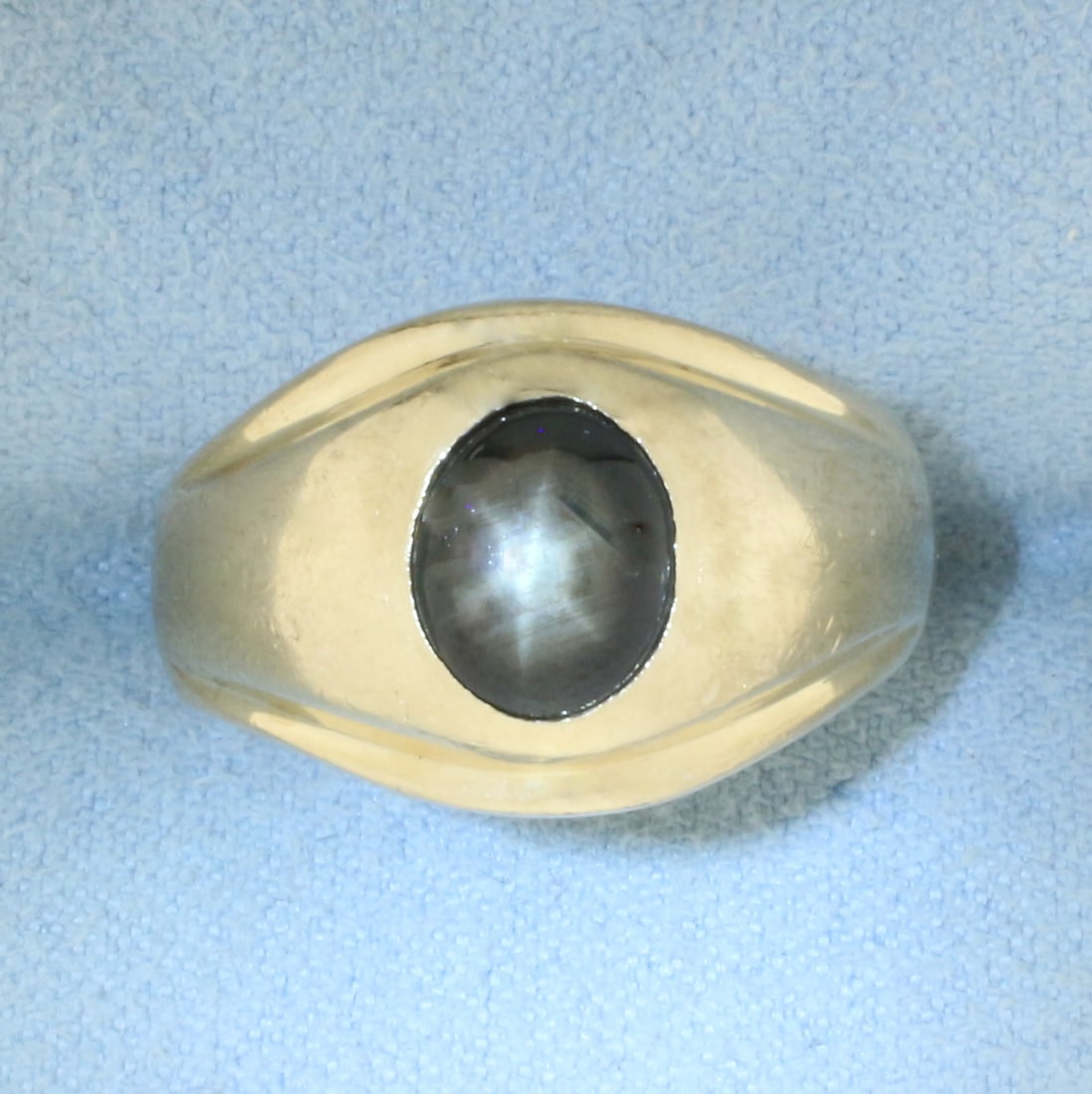 Mens Star Sapphire Ring in 14k Yellow Gold: In 14k Yellow Gold. Contains one 9x7mm high quality natural Black Star Sapphire gemstone with distinct "star" under light. 13.4mm wide at top of ring. Size 9.5. 8.8g.