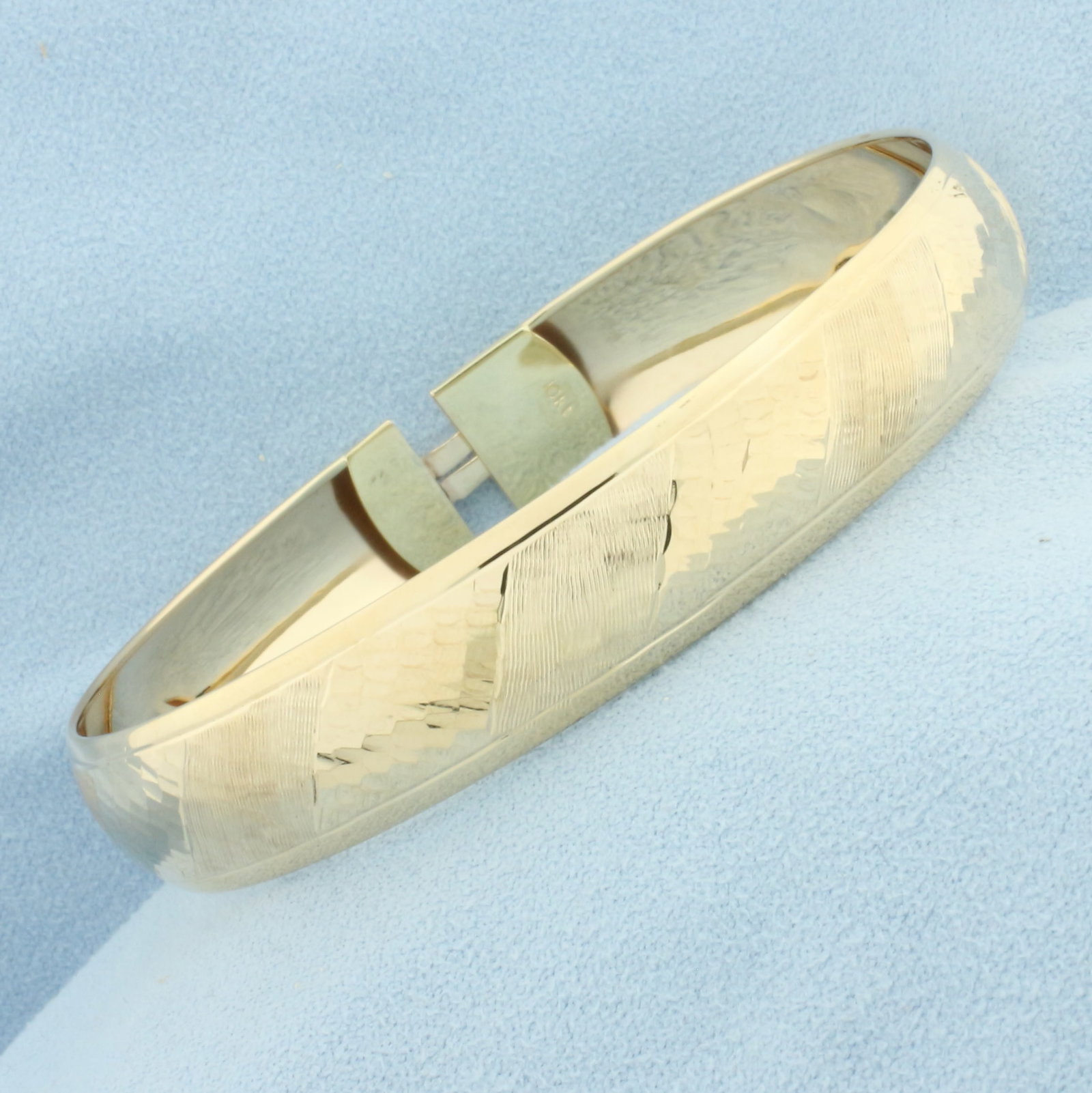 Etched Stripe Design Bangle Bracelet in 10k Yellow Gold: In 10k Yellow Gold. Interior dimensions: 2 1/2 inch by 2 1/4 inch. 11.8mm wide. Slide clasp. 6.1g.