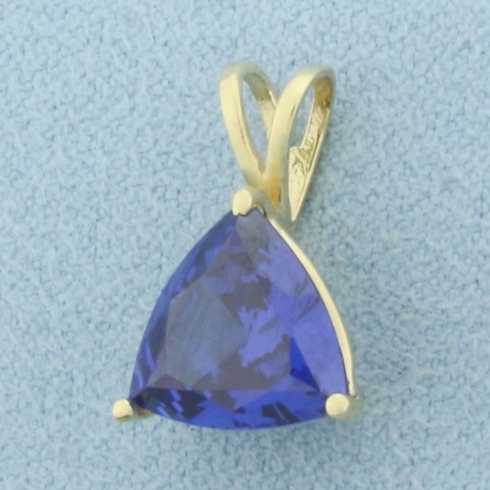 AAA Tanzanite Pendant in 14k Yellow Gold: In 14k Yellow Gold. Contains one 10mm AAA quality trillion cut natural Tanzanite gemstone, approximately 2.5ct, with intense sapphire color and excellent clarity. 5/8 inch long. 3/8 inch wide. 1.9g.