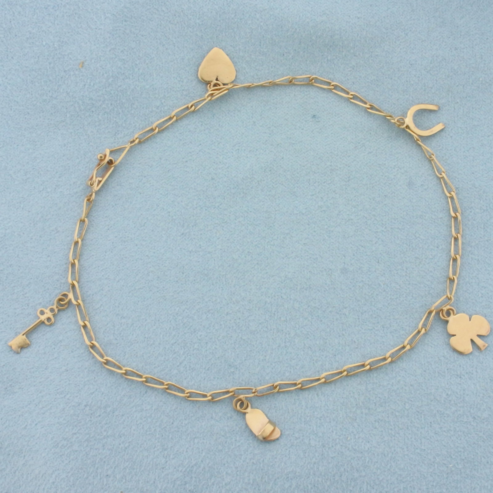 Charm Anklet in 18k Rose Gold: In 18k Rose Gold. 9 1/4 inches long. 2mm chain wide. Heart, key, horse shoe, sandal, and clover charms. Locking clasp with safety latch. 3.8g.