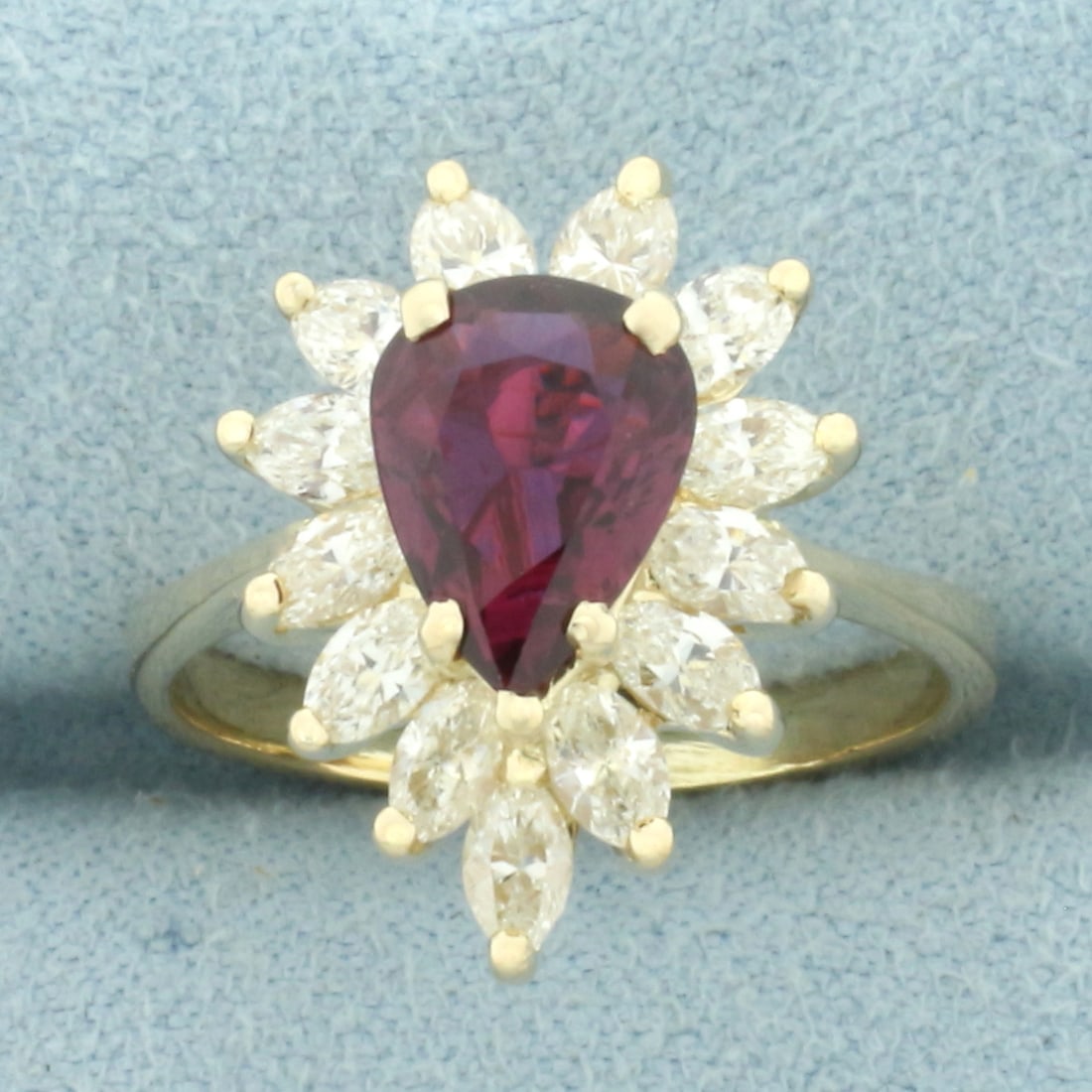 Pear Cut Ruby and Diamond Halo Ring in 14k Yellow Gold: In 14k Yellow Gold. Contains one high quality natural 1.5ct pear Ruby gemstone with intense color and excellent clarity. Also contains thirteen high quality marquise diamonds, 3/4ct TW, VS clarity/J c