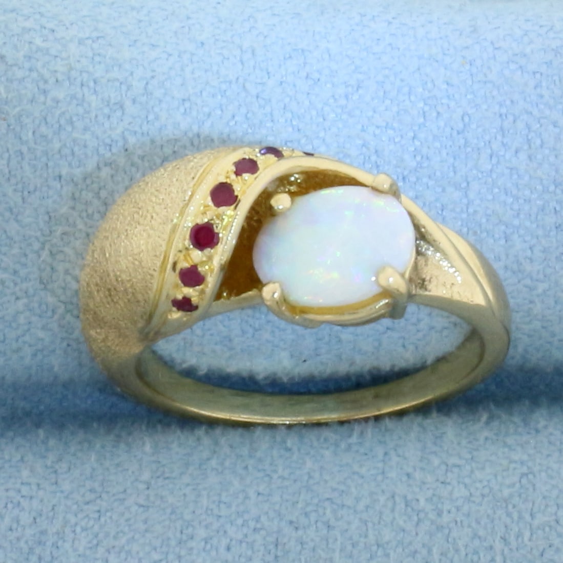 Opal and Ruby Ring in 14k Yellow Gold: In 14k Yellow Gold. Contains one high quality 8mmx6mm natural Opal gemstone with intense play of color and flashes of green, blue, orange, and red. Also contains seven high quality 1.2mm natural Ruby 