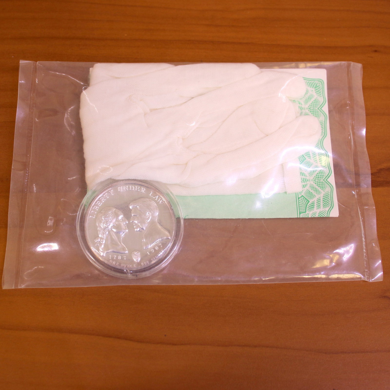 1987 Liberty Under Law US Constitution 1oz Silver Coin: Contains one 1987 Constitutional Bicentennial Liberty Under Law 1oz .999 Silver Coin. Includes gloves and certificate of authenticity in sealed package.