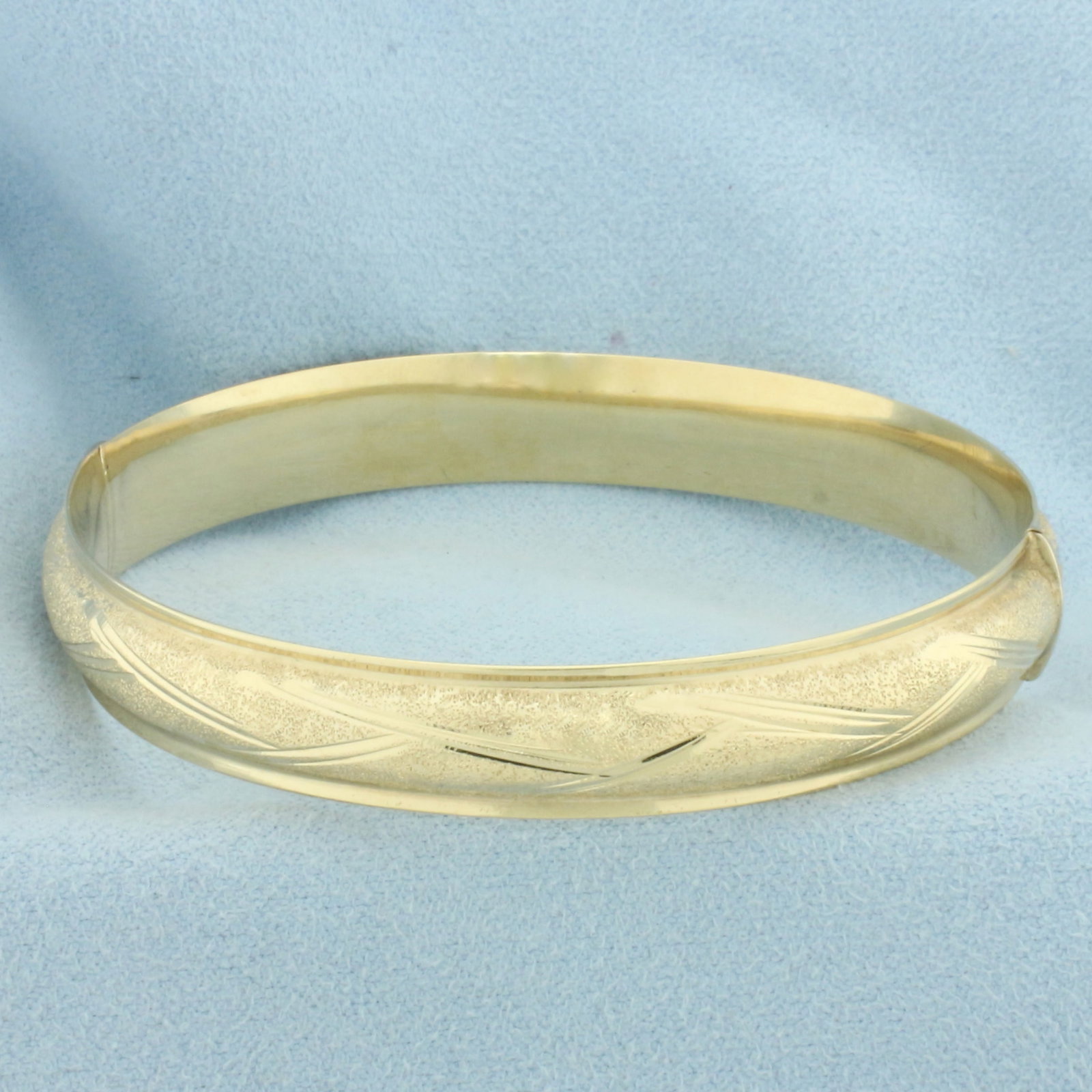 Hinged Sandblast Finish Diamond Cut Bangle Bracelet in 14k Yellow Gold: In 14k yellow gold. 9.5mm wide. Interior dimensions: 2 3/8 inches by 2 1/8 inches. Sparkle sandblast finish with diamond cut design. Slide closure. 11.2g.