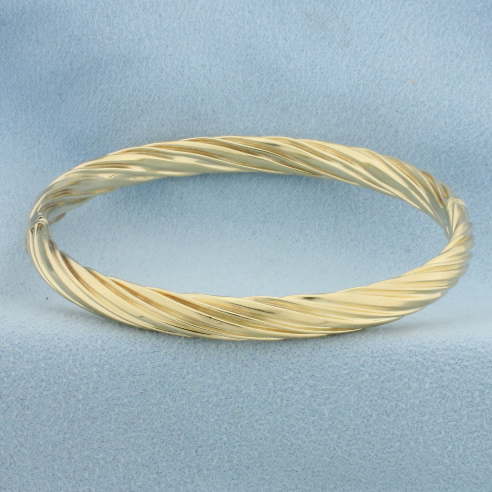 Twisting Design Bangle Bracelet in 14k Yellow Gold: In 14k Yellow Gold. Interior dimensions: 2 1/4 inch by 2 1/8 inch. 6mm wide. Hinged closure. 9.5g.