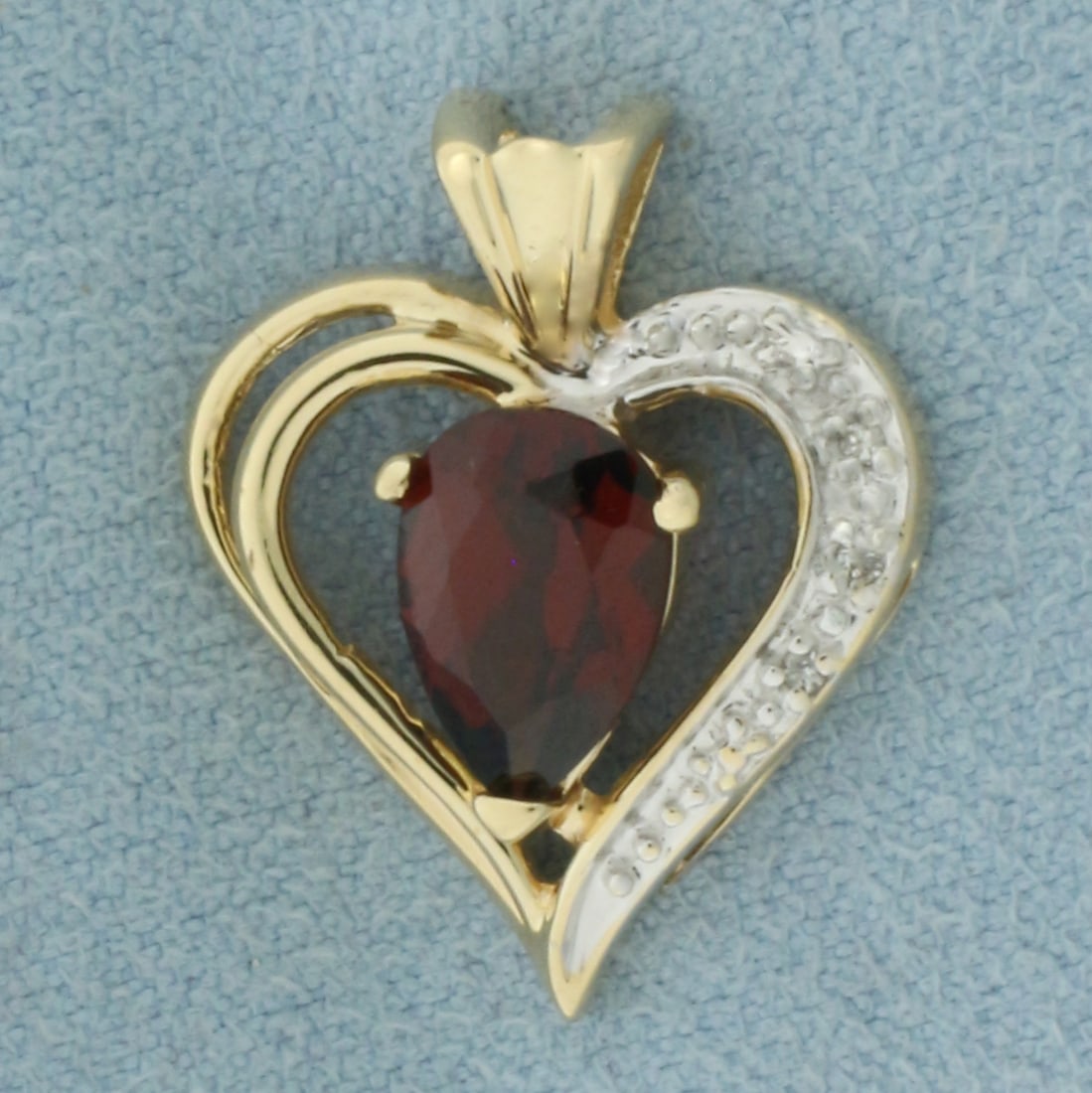 Garnet and Diamond Heart Pendant in 14K Yellow Gold: In 14K Yellow Gold. 3/4 inch long. 5/8 inch wide. Contains one high quality natural pear cut garnet, 6x9mm, approximately 1.3ct, with vibrant color and excellent clarity. Also contains three high qual