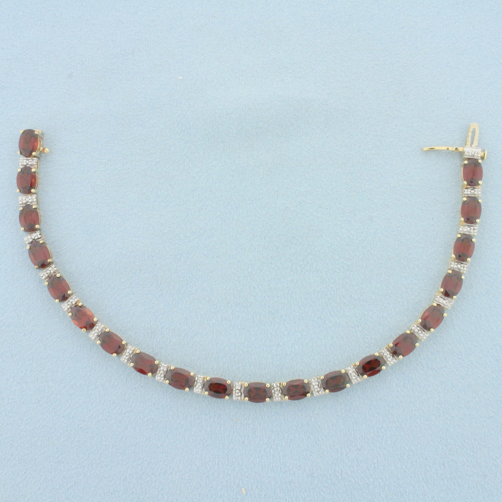 Garnet and Diamond Tennis Bracelet in 14k Yellow Gold: In 14k yellow Gold. Contains 20 high quality natural 1ct oval garnet gemstones with intense color and excellent clarity. Also contains forty 1/2pt diamonds. Concealed slide closure with safety latch. 