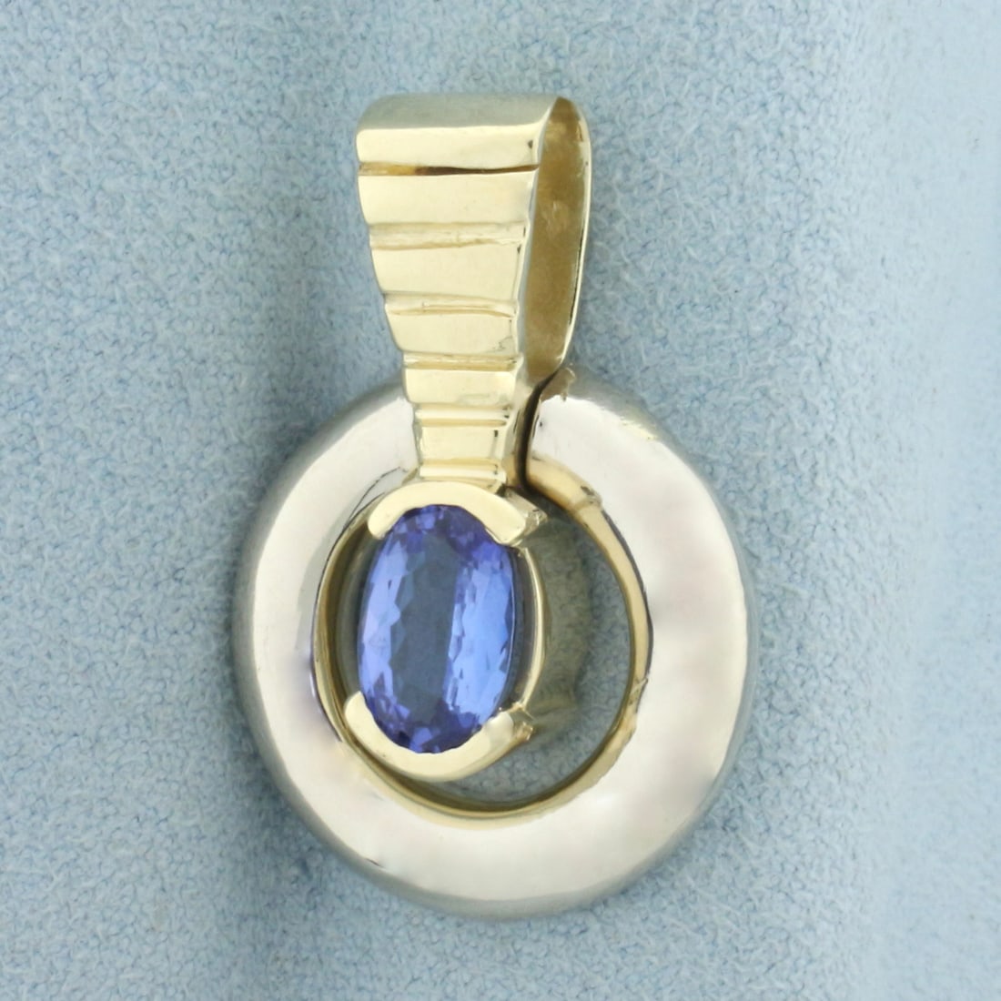 Tanzanite Two Tone Pendant in 14k Yellow and White Gold: In 14k yellow and white gold. Contains one high quality natural 1.5ct AAA quality oval cut Tanzanite Gemstone, 9mm by 6mm, with beautiful saturated blue color and excellent clarity. Gemstone "swings" 
