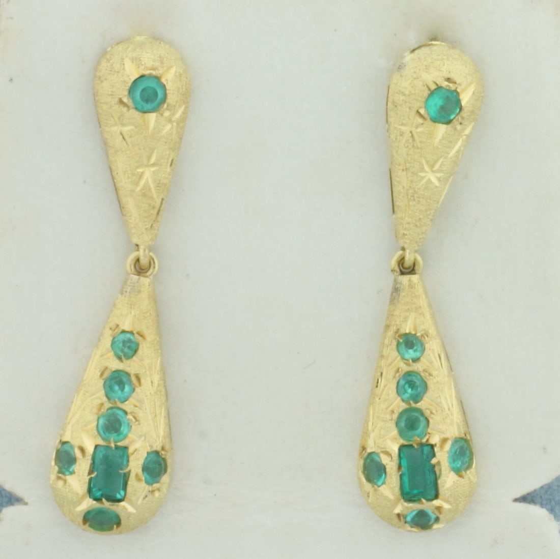 Emerald Dangle Earrings in 18k Yellow Gold: In 18k Yellow Gold. Contains two 3.7mm emerald cut and fourteen 2mm round quality natural Emerald gemstones with vibrant color and excellent clarity. 1 3/8 inch long. 1/4 inch wide. Friction backs.