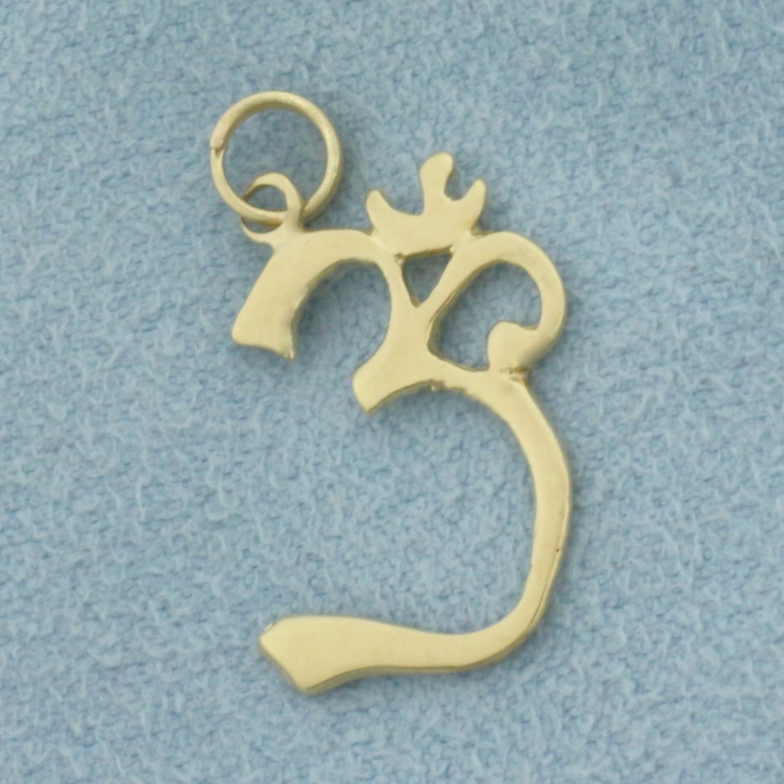 Om Hindu Symbol Charm in 14k Yellow Gold: In 14k Yellow Gold. 7/8 inch long (including spiral jump ring for easy putting on/taking off). 1/2 inch wide at widest. The Om symbol is the most sacred syllable, mantra, and symbol in Hinduism, repre