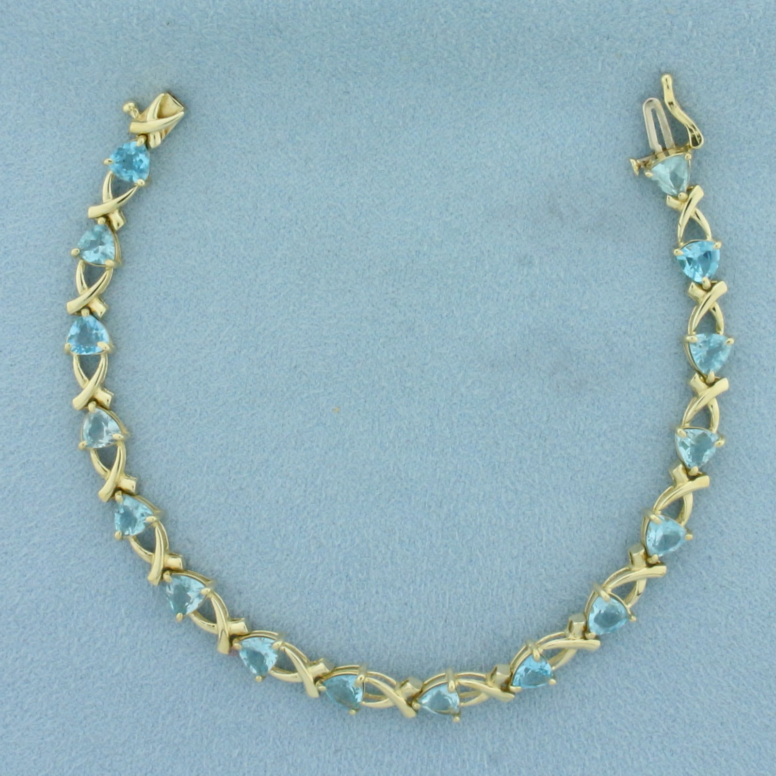 Sky Blue Topaz X Link Bracelet in 10k Yellow Gold: In 10K Yellow Gold. 7 1/8 inches long. Contains 16 high quality natural 5mm trillion cut Sky Blue Topaz gemstones with bright color and excellent clarity. Slide clasp with safety latch.