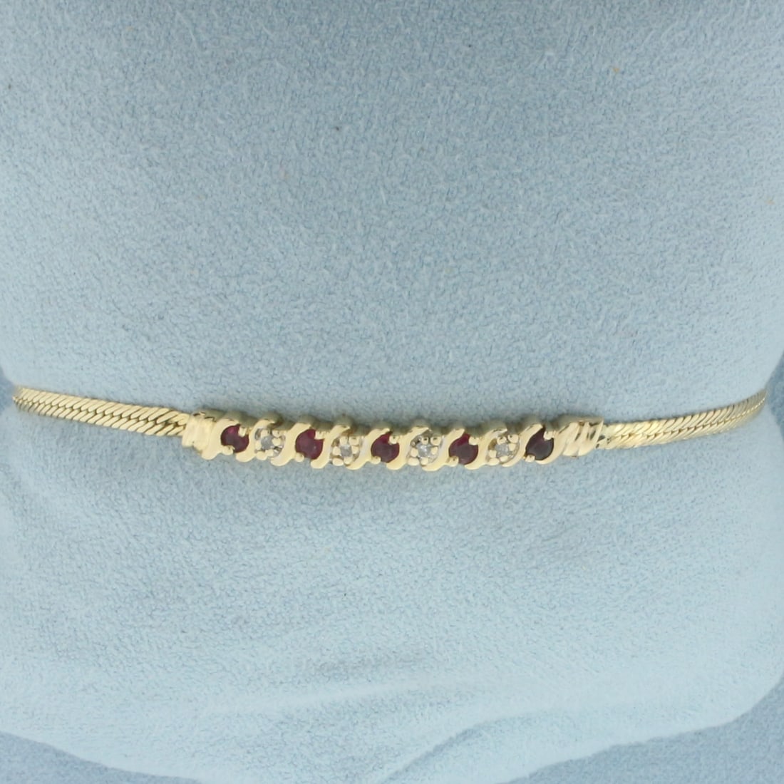 Ruby And Diamond Bracelet in 14k Yellow Gold: In 14k yellow gold. 7 inches long, 4mm wide. Contains 5 Ruby gemstones, 2.5mm each, with vibrant color and excellent clarity. Also contains 4 high quality 1/2pt diamonds. Lobster clasp. 4.8g.