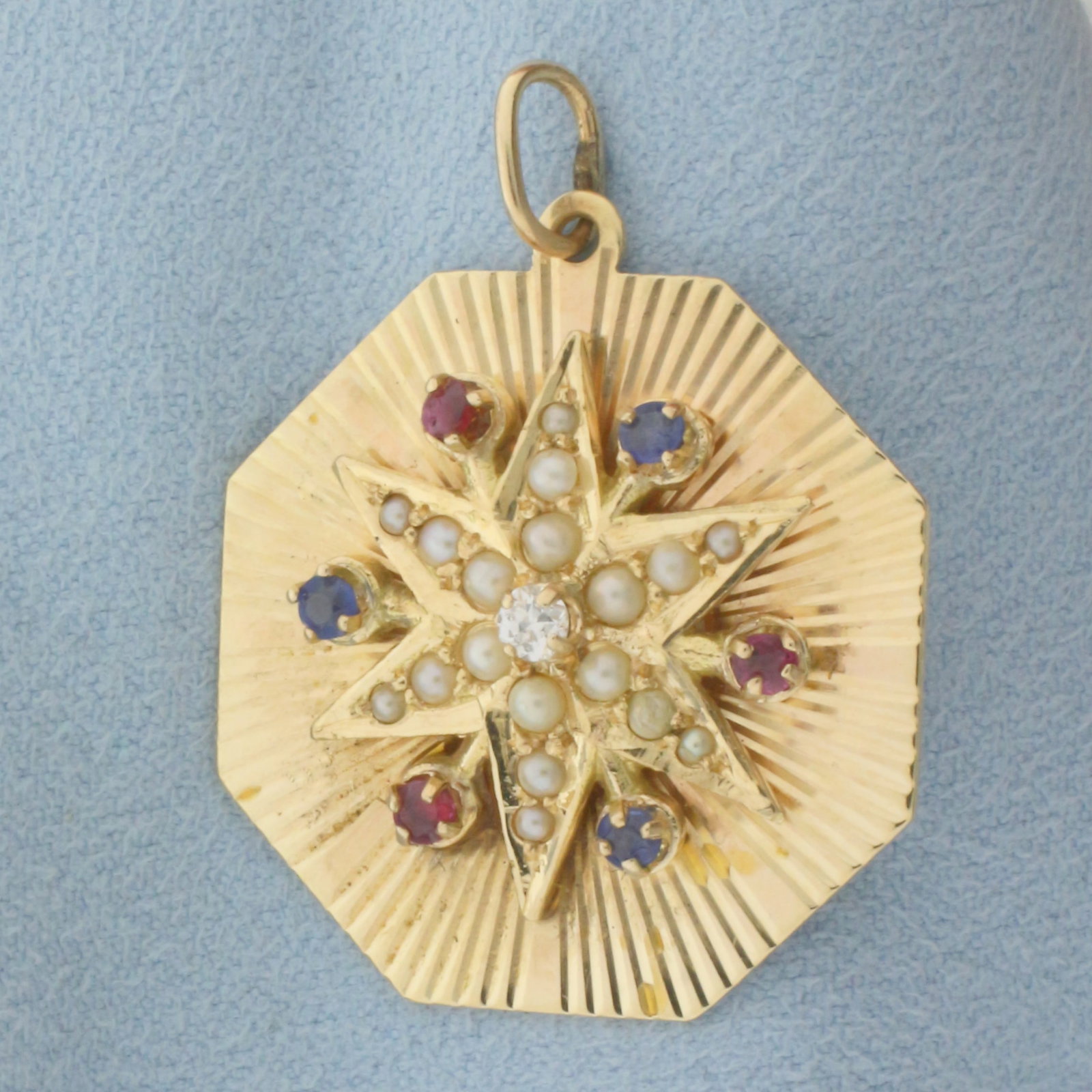 Diamond, Ruby, Sapphire, and Pearl Medallion Pendant in 14k Yellow Gold: In 14k Yellow Gold. Contains one .07ct high quality diamond, SI clarity/H color. Also contains three Ruby and three Sapphire high quality 2.5mm gemstones with vibrant color. Also contains eighteen 1.5