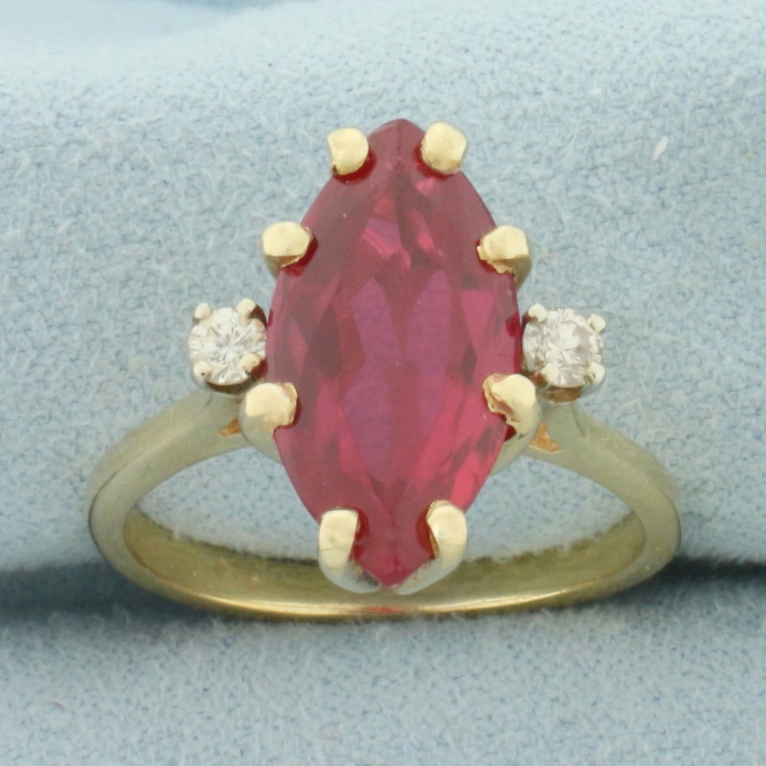 Vintage Marquise Lab Ruby and Diamond Ring in 14k Yellow Gold: In 14k Yellow Gold. Contains one 16x8mm high quality marquise Lab created Ruby gemstone, approximately 4.5cts, with intense color and excellent clarity. Also contains two .07ct high quality diamonds, 