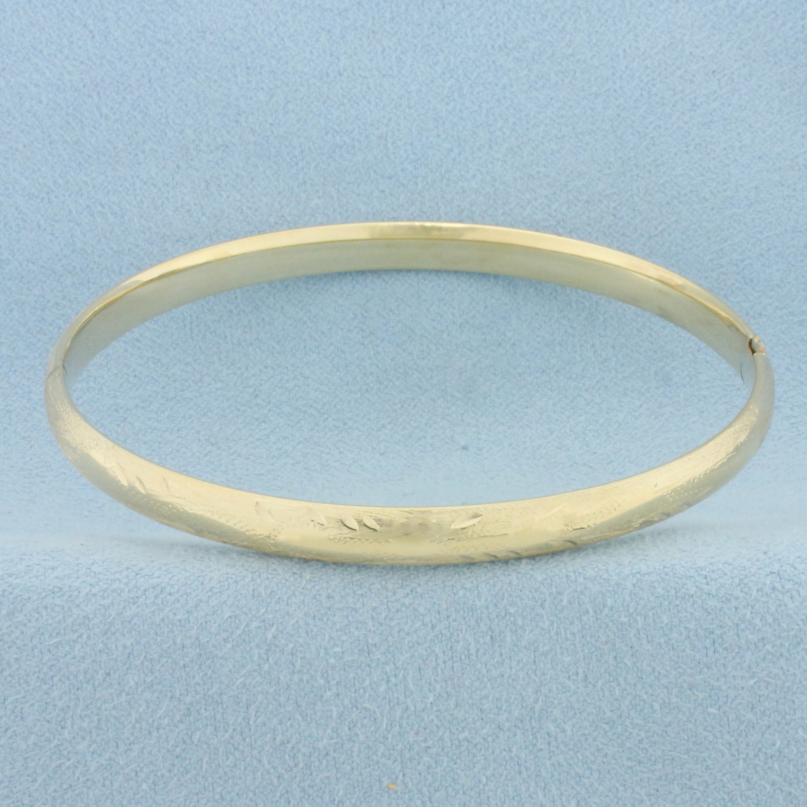 Engraved Flower Design Bangle Bracelet in 14k Yellow Gold: In 14k Yellow Gold. Interior dimensions: 2 1/4 inch by 2 1/8 inch. 5mm wide. Hinged closure. 4.9g.