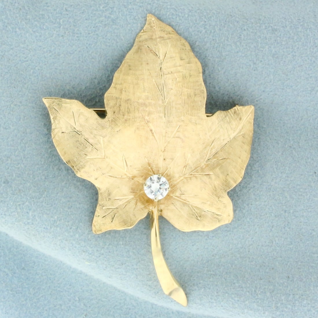 Maple Leaf Diamond Brooch Pin in 14K Yellow Gold: In 14K Yellow Gold. Contains one high quality 1/3ct round brilliant Diamond, VS clarity/G color. 1 1/8 inches long. 1 1/2 inch wide. 11.8g