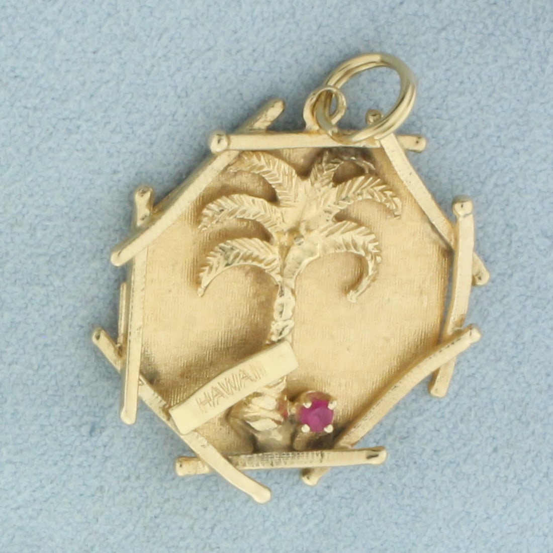 Engravable Hawaii Palm Tree Ruby Charm or Pendant in 14k Yellow Gold: In 14k Yellow Gold. Contains one 2mm high quality natural Ruby gemstone with intense color and excellent clarity. 1 1/4 inch long including bale. 1 inch wide. Split ring for easy attachment to bracele